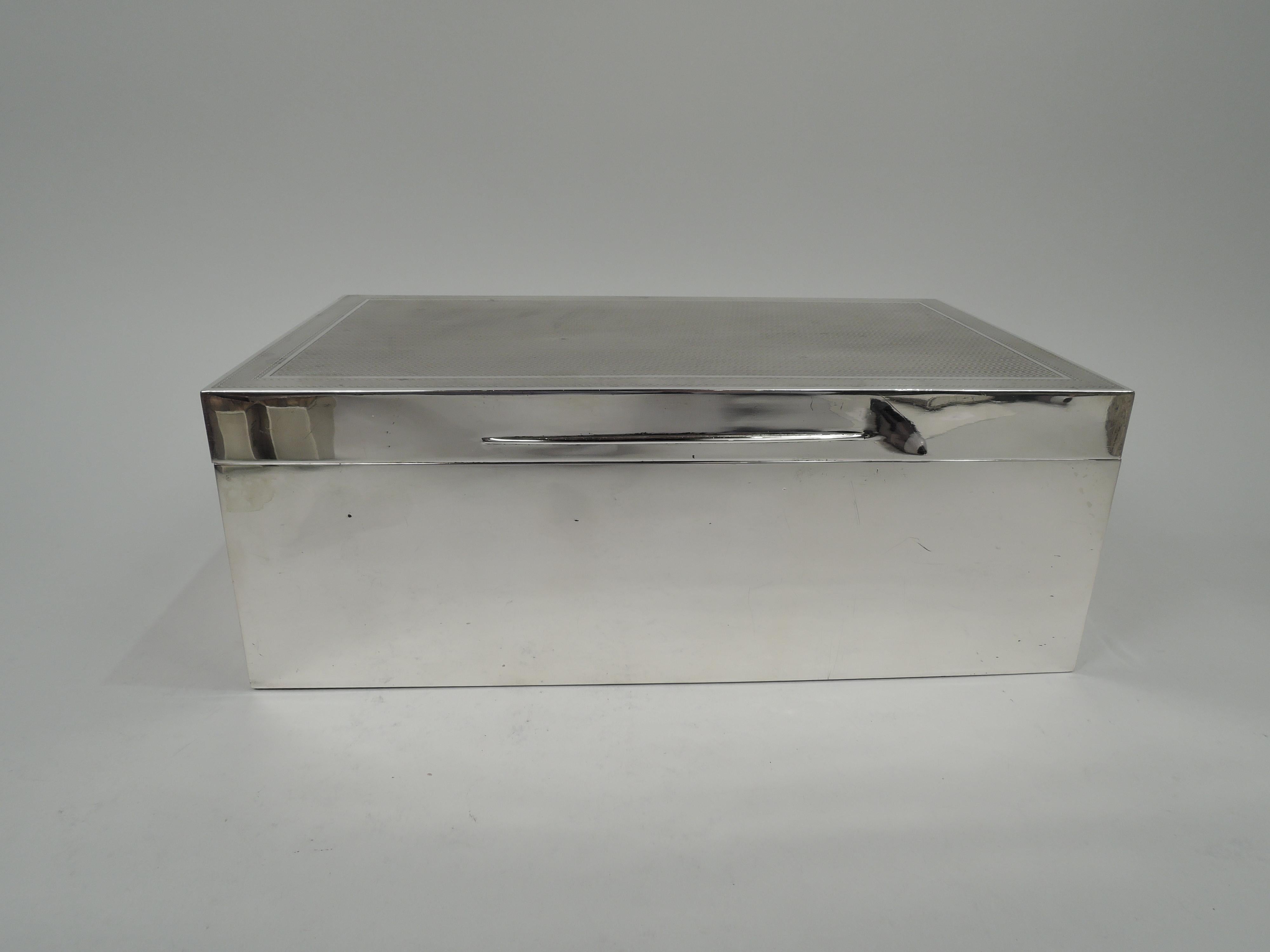 George V sterling silver cigar box. Made by Barnard & Sons, Ltd in London in 1930. Rectangular with straight sides. Cover hinged and with tapering tab; top flap with engine-turned linear pattern bordered by wraparound lines between wavy lines.