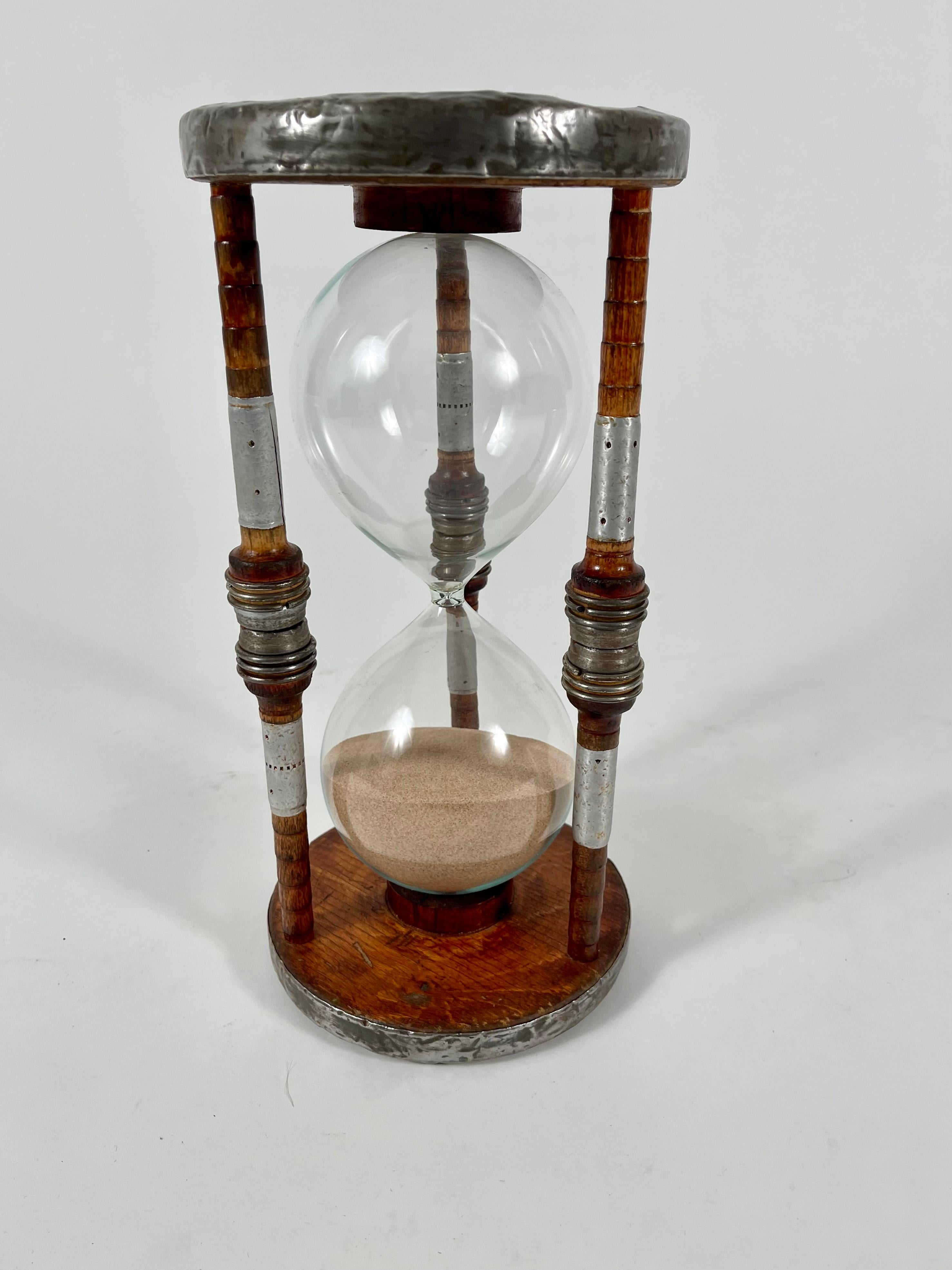An antique English bobbin one hour hourglass sand timer. Crafted from original antique bobbins and spools which were used to wind thread in Victorian cotton mills, the bases bear the impressed original marks of 