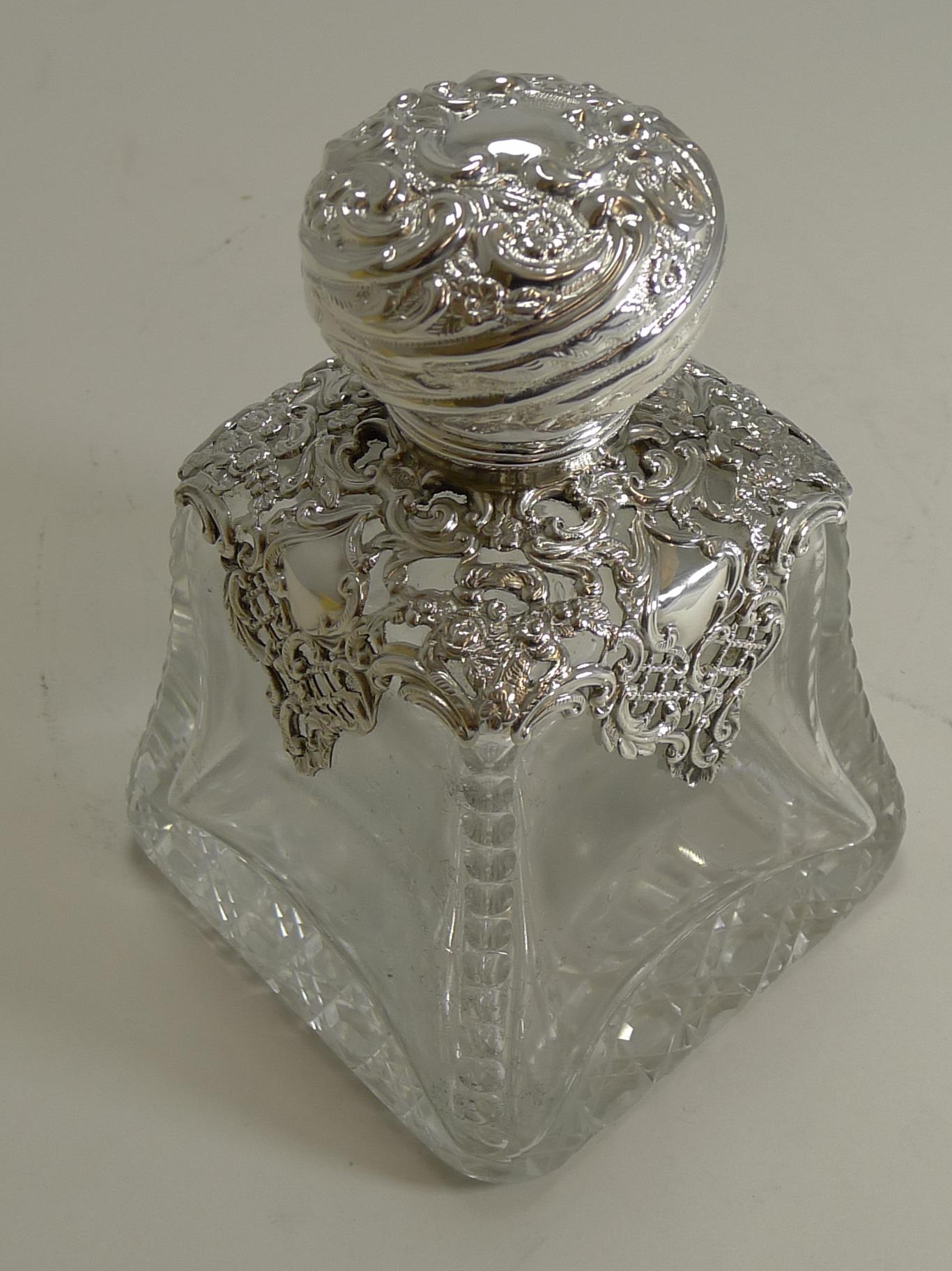 This wonderful and impressive perfume bottle was made from a hefty piece of English crystal with hobnail cutting to the underside and an elegant cut down each corner of the glass.

The hinged lid and applied pierced or reticulated mount that is