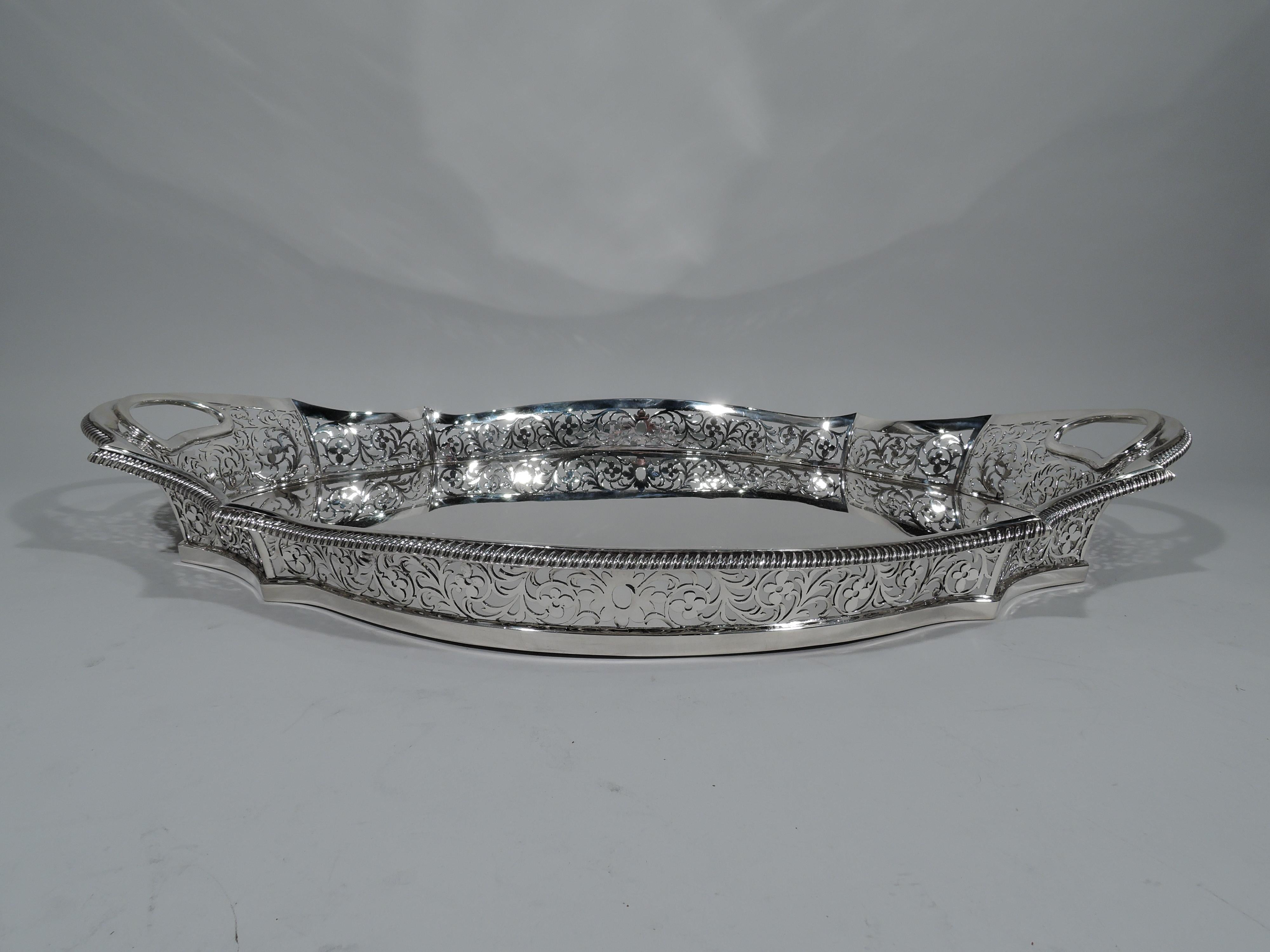 Edwardian sterling silver tray. Made by Charles Frederick Hancock in London in 1908. Shaped oval with solid well. Sides have pierced floral scrolls. Rim gadrooned. Cutout lunette end handles. Pretty and substantial with impressive heft. Fully