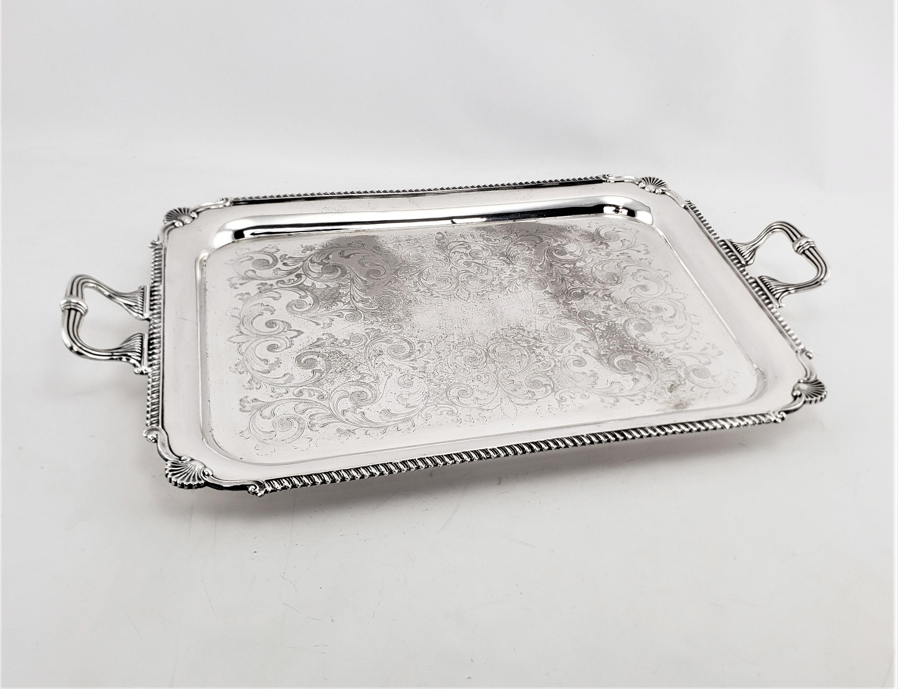 This large silver plated serving tray shows no maker's mark, but did originate from England and date to approximately 1920 and done in an Edwardian style. The tray has nice stylized fans on each of the corners and ribbed ribbon styled handles. The