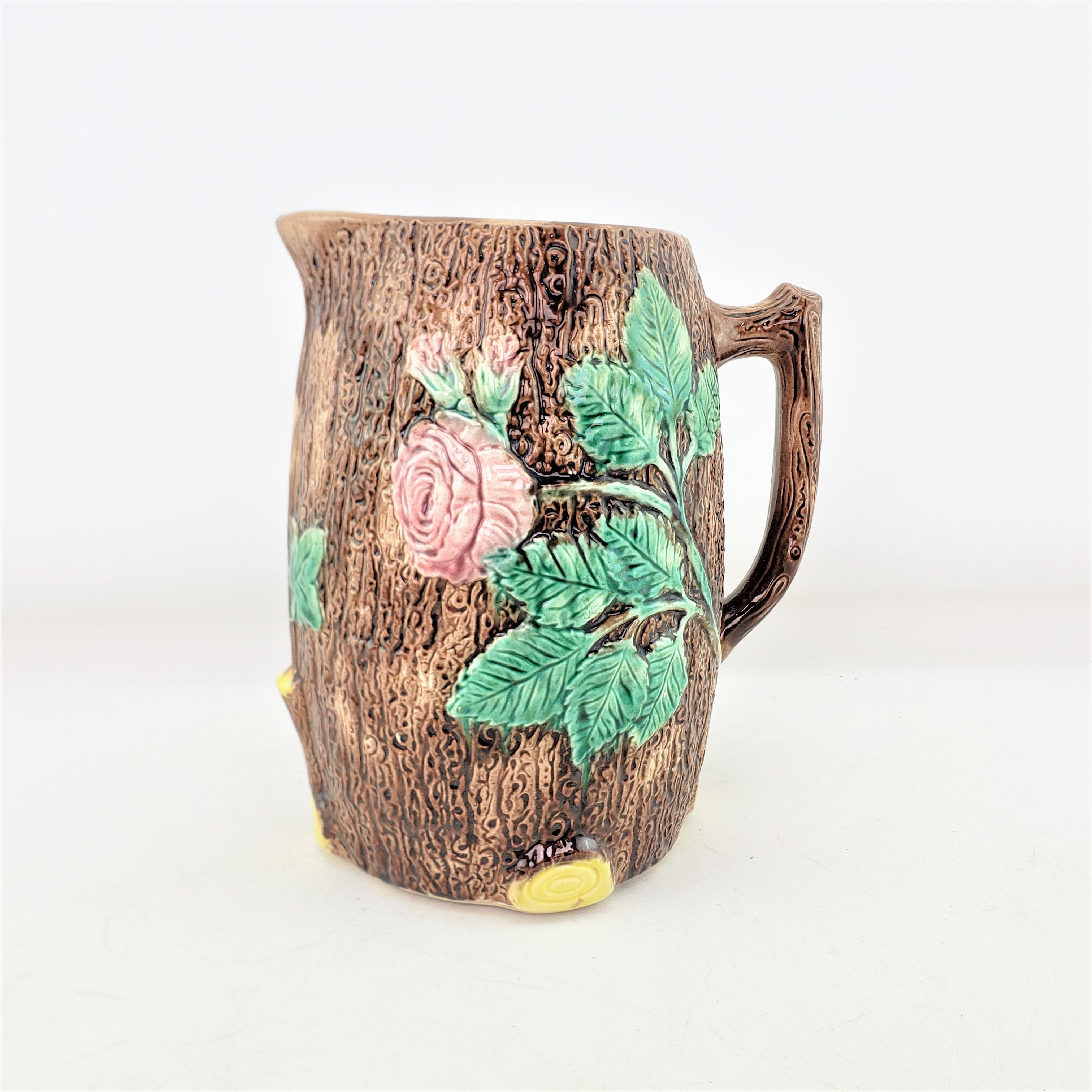 This large antique pitcher is unsigned, but presumed to have originated from England and date to approximately 1920 and done in a Victorian style. The pitcher is composed of majolica and decorated with a wood grain background with raised leaves and