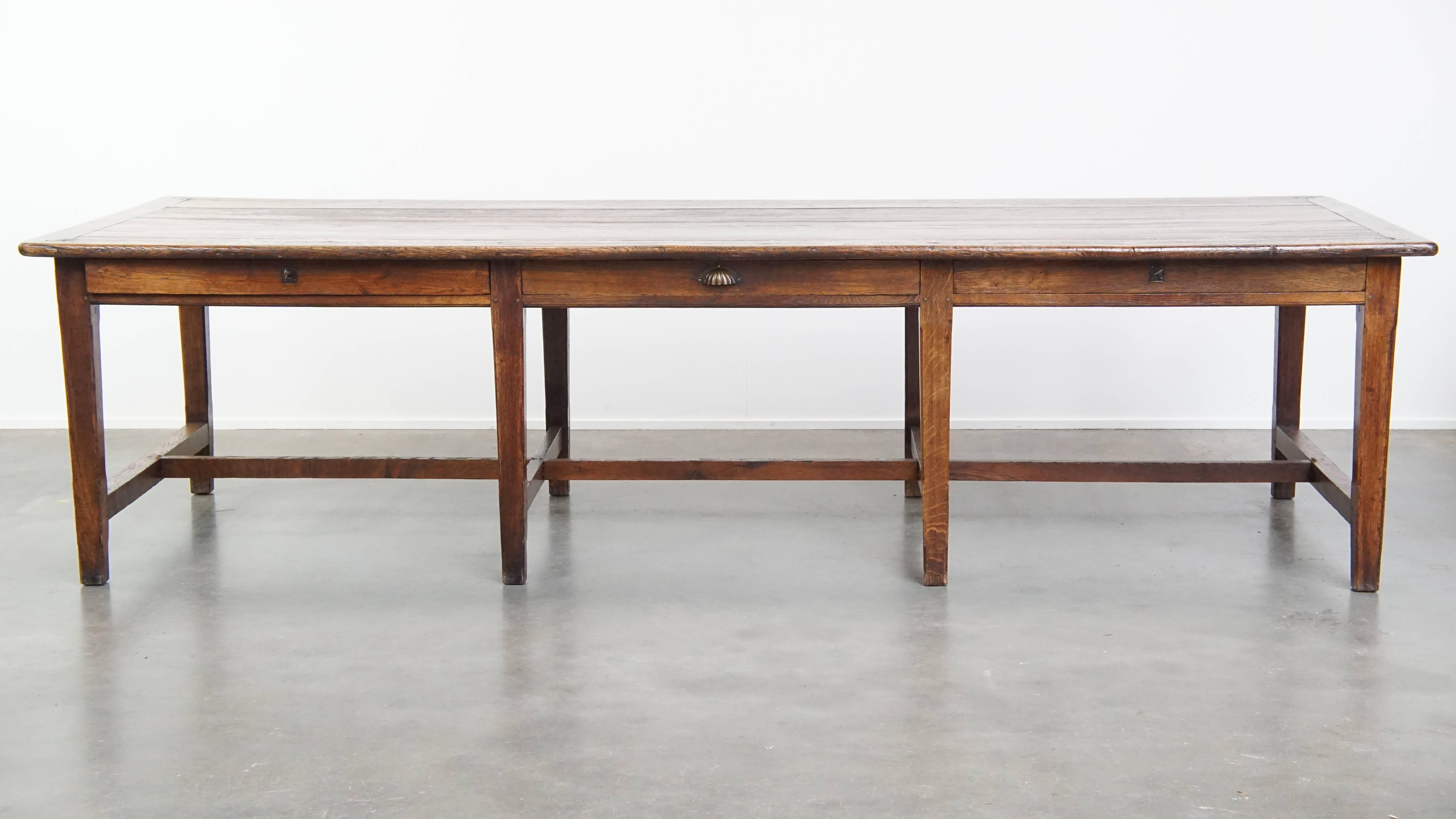 Offered here is this stunning and uniquely large antique English oak dining table from the early 19th century, featuring a beautiful patina. Crafted from oak, this grand English dining table has developed a rich patina over the years, making it a