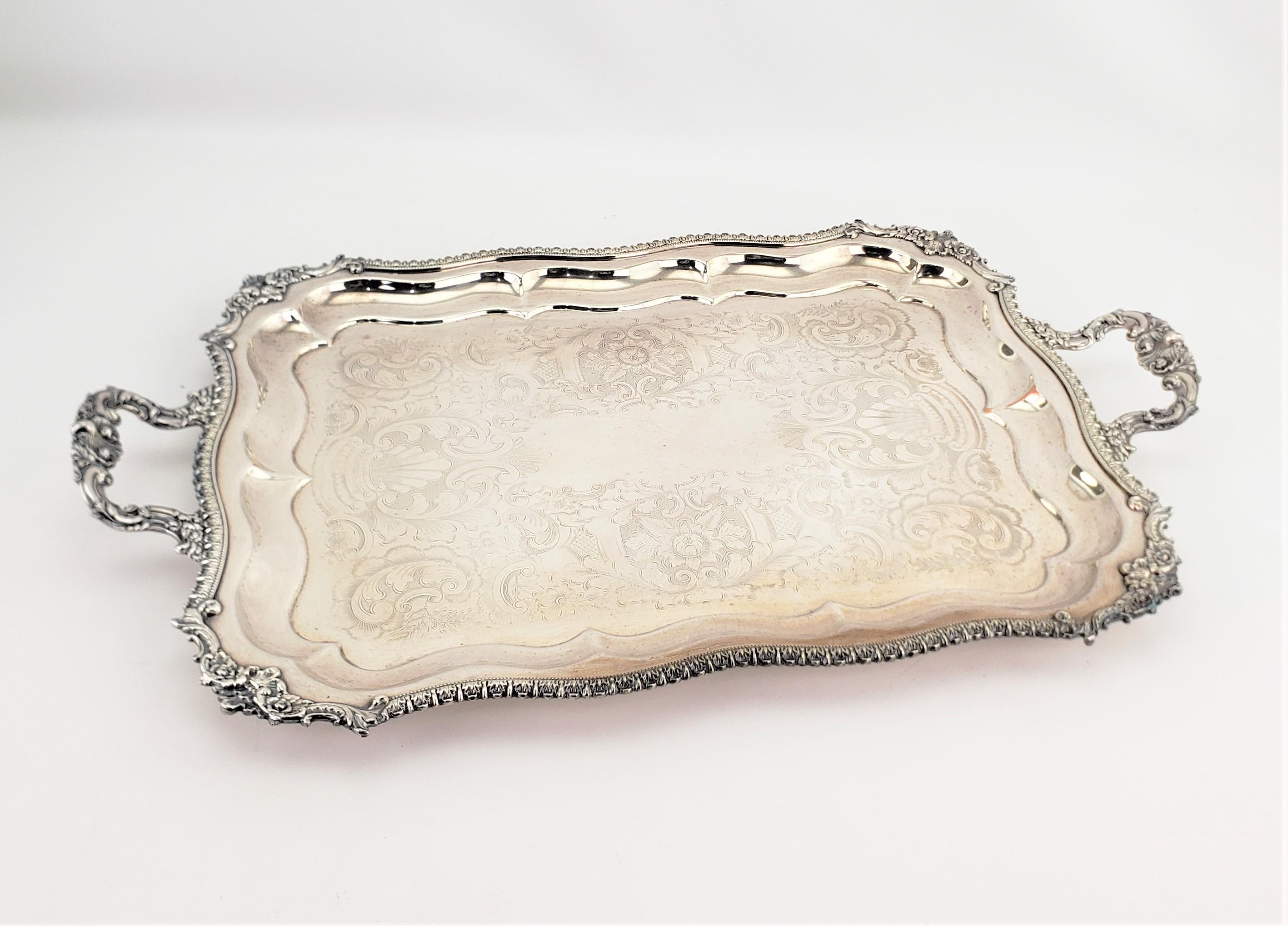 This large and substantial silver plated serving tray is hallmarked by an unknown maker and originates from England, dating to approximately 1920 and done in a Victorian style. The perimeter of the tray is done with a heavy beaded decoration, and