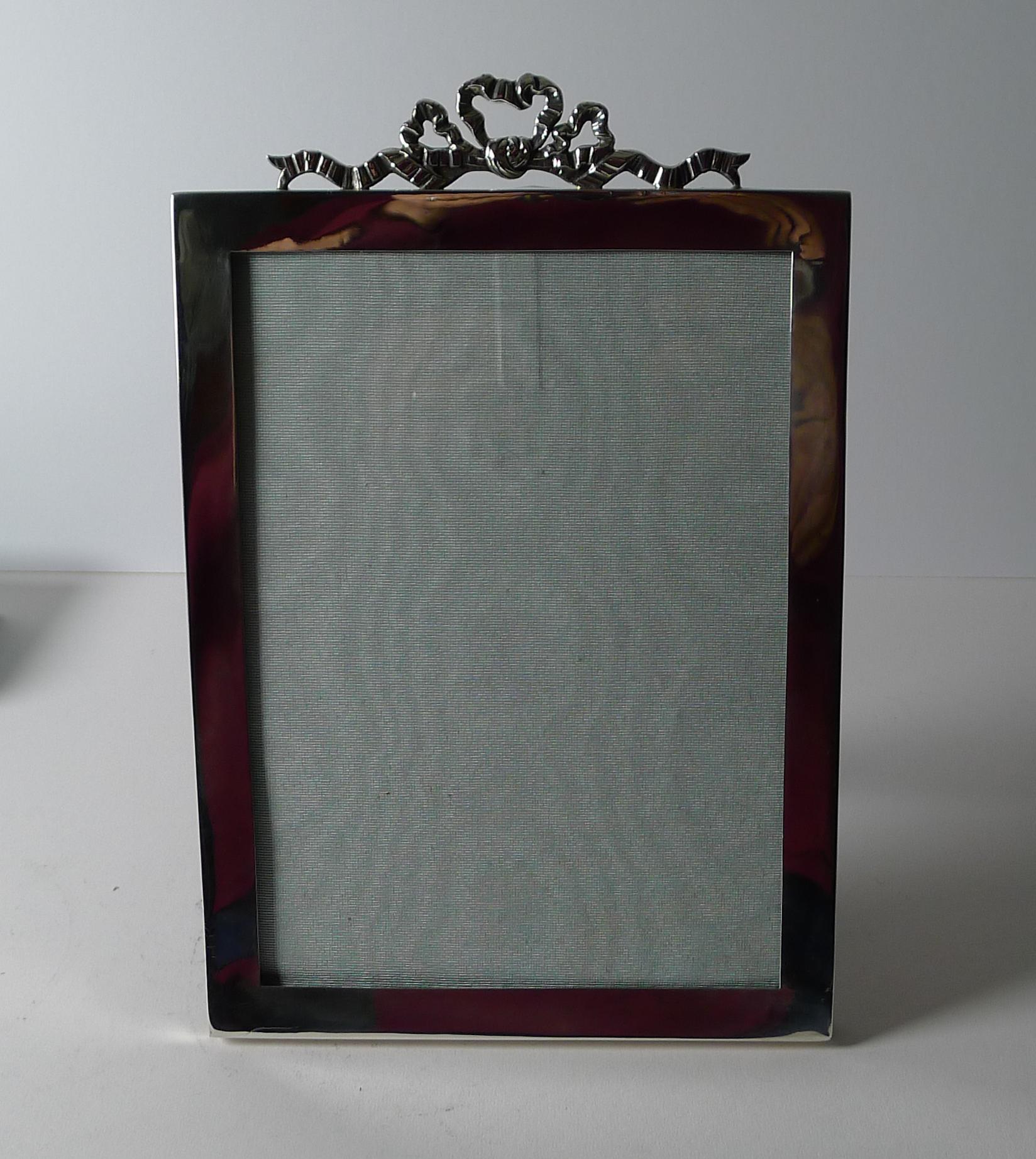 A stunning English Edwardian frame made from solid / sterling silver fully hallmarked for London 1906.  The makers mark is also present for F W Hentsch.

The frame is topped with a stunning Ribbon and Bow mount and the backing is made from solid