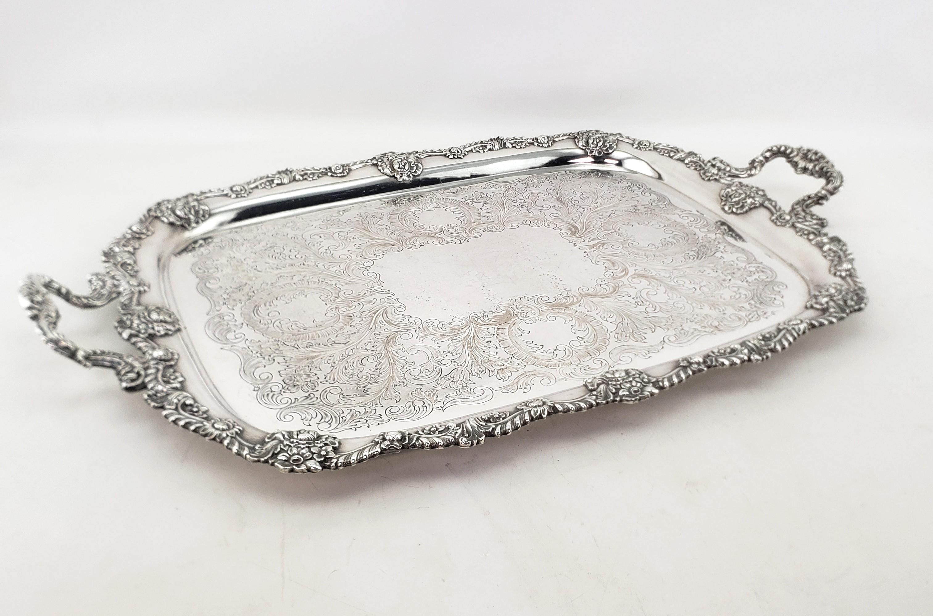 This very large and substantial antique serving tray is hallmarked by an unknown maker, but originated from England and dates to approximately 1880 and done in the period Victorian style. The tray is composed of silver plate and features an ornate