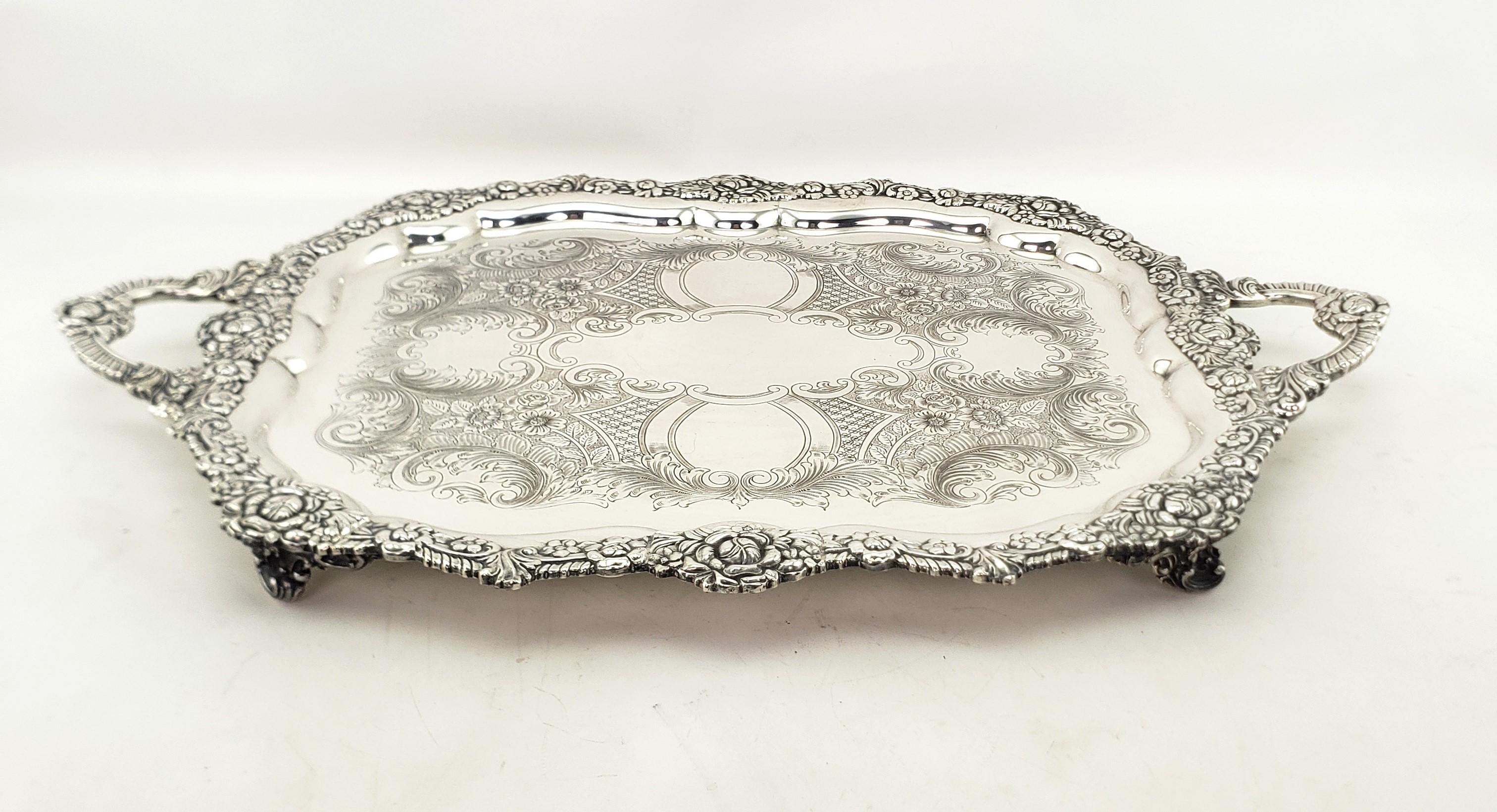 This very large and substantial antique footed serving tray is hallmarked by an unknown maker, but originated from England and dates to approximately 1880 and done in the period Victorian style. The tray is composed of silver plate and features an