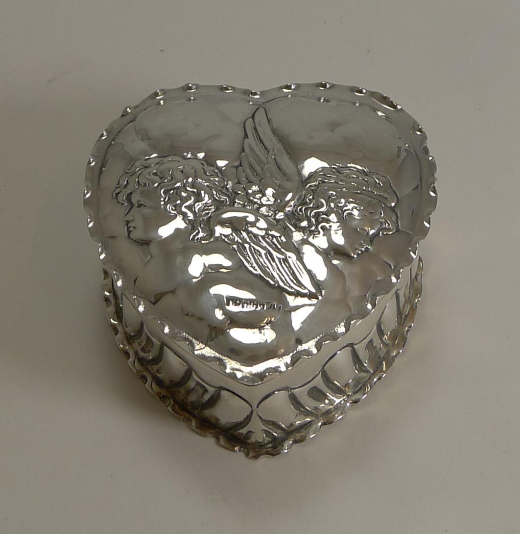 A handsome large Victorian heart shaped trinket box with a pair of winged Cherubs / Angels to the lid and an English registration number underneath.

The sides of the heart with embossed or repousse fluted decoration. The hinged lid fits well and