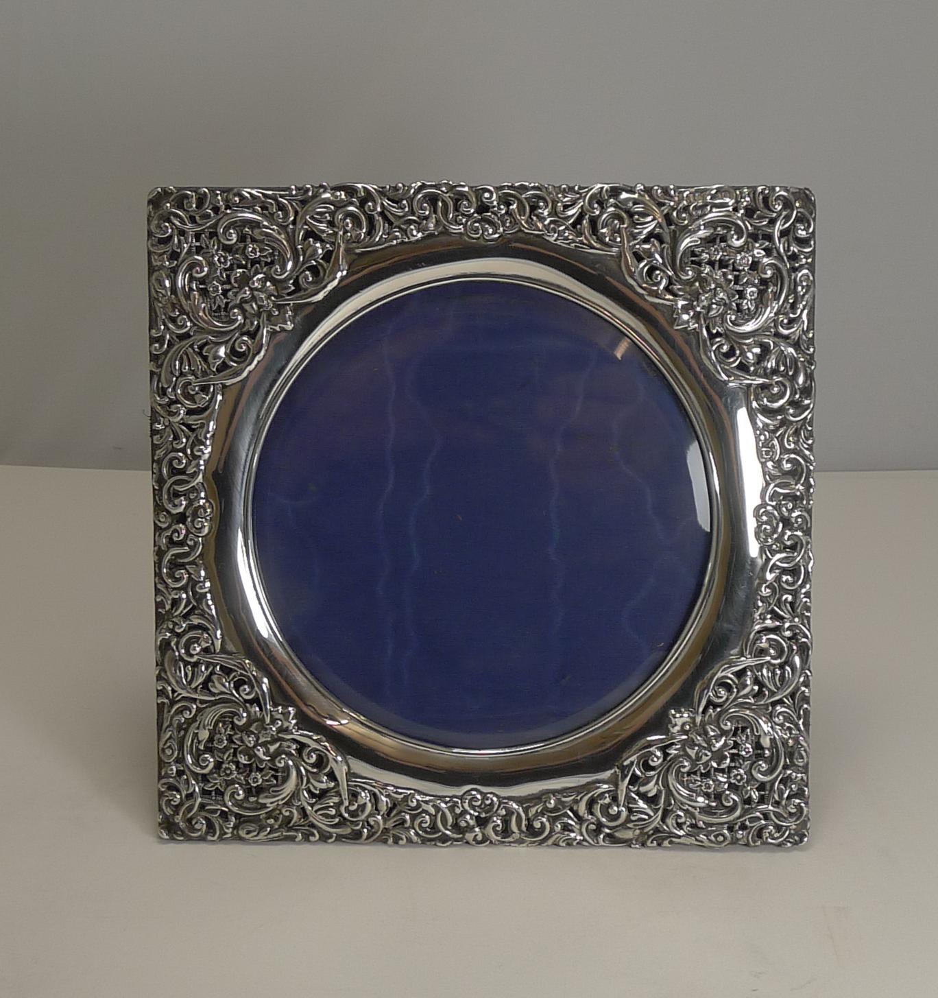 A stunning Edwardian photograph frame made from pierced or reticulated sterling silver, beautifully decorated with a mythical face in each corner surrounded with floral and foliate motifs, with hand chased highlights.

The square frame has a
