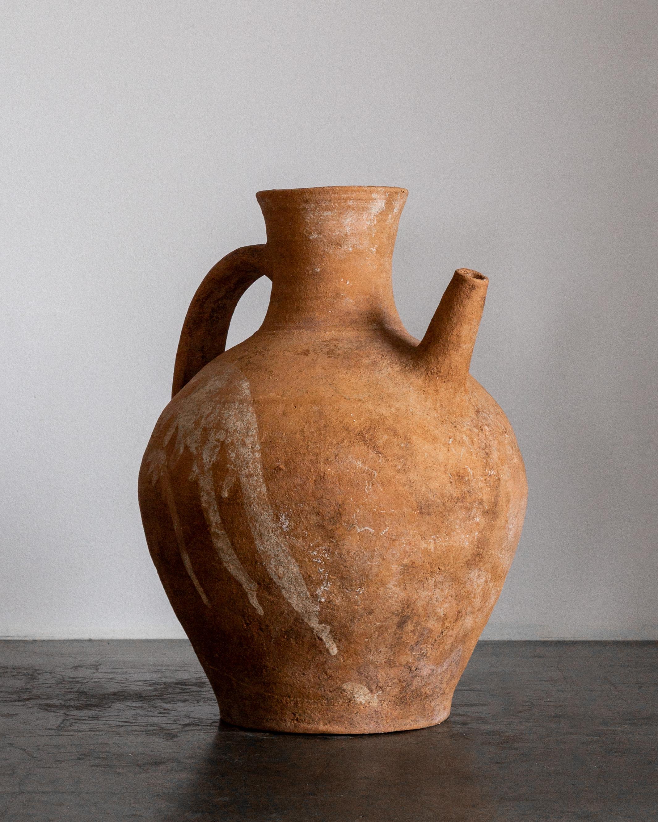 Jarra de vino (cruche) europea de terracota, principios del siglo XX, con un diseño tradicional de una sola asa y un característico pico vertedor. Esta antigua vasija ejemplifica la maestría artesanal de la alfarería popular con sus proporciones