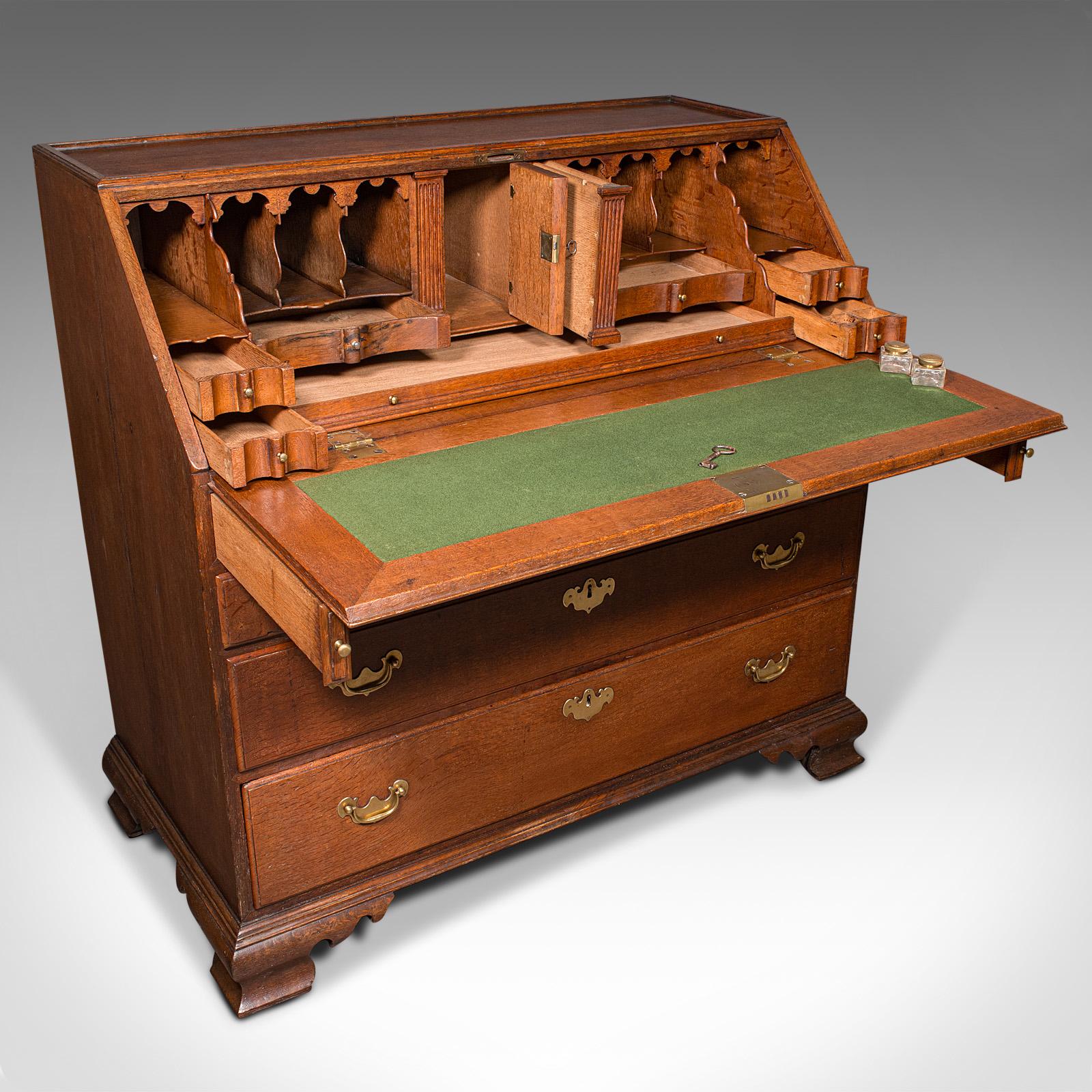 This is a large antique fall-front bureau. An English, oak five-drawer writing cabinet, dating to the Georgian period, circa 1750. Exuding refined 18th century craftsmanship, this bureau presents a beautifully executed writing interior with fine