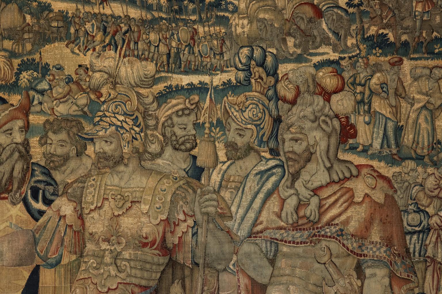 Large pre-19th century historical Flemish tapestry composed of handwoven wool. The piece is heavily detailed with classical figures in the foreground and a landscape scene in the background featuring armies and individuals riding elephants.