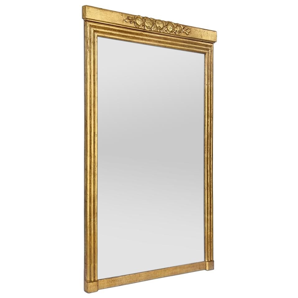 Large French Art Nouveau-style gilded wood mantel mirror, circa 1900. Decorated with a pediment of stylized flowers and a fluted frame around the glass mirror. Patinated leaf gilding. Pediment width: 13 cm / 5.11 in. Frame width: 6.5 cm / 2.55 in.