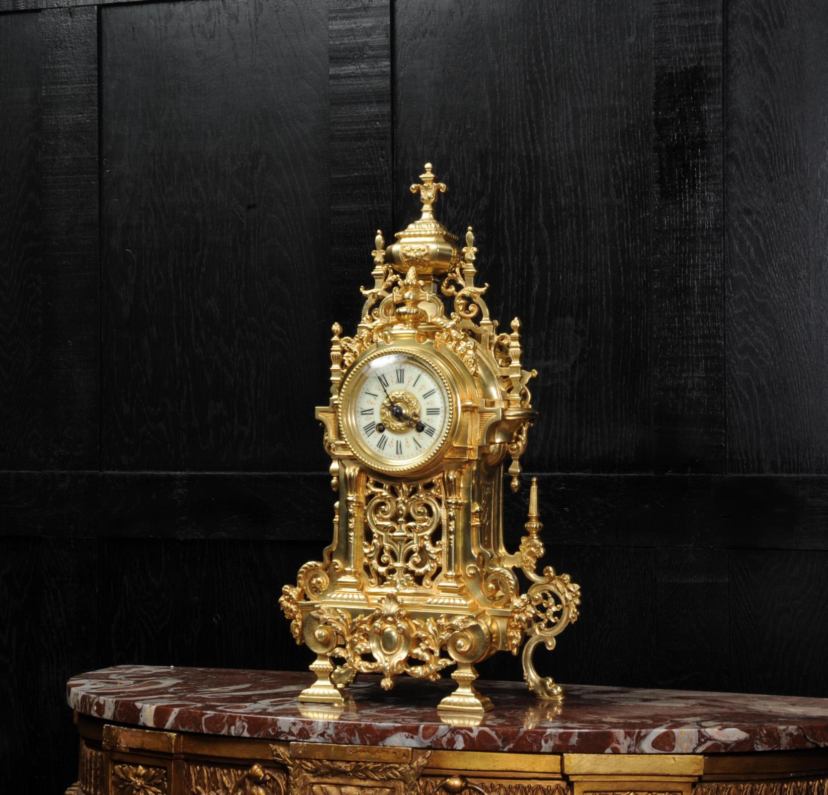 A large and stunning antique French gilt bronze Baroque clock, dating from 1900. It is styled with profuse acanthus decoration applied to the architecturally shaped case. The front is fretted with scrolling acanthus to allow the pendulum to be seen