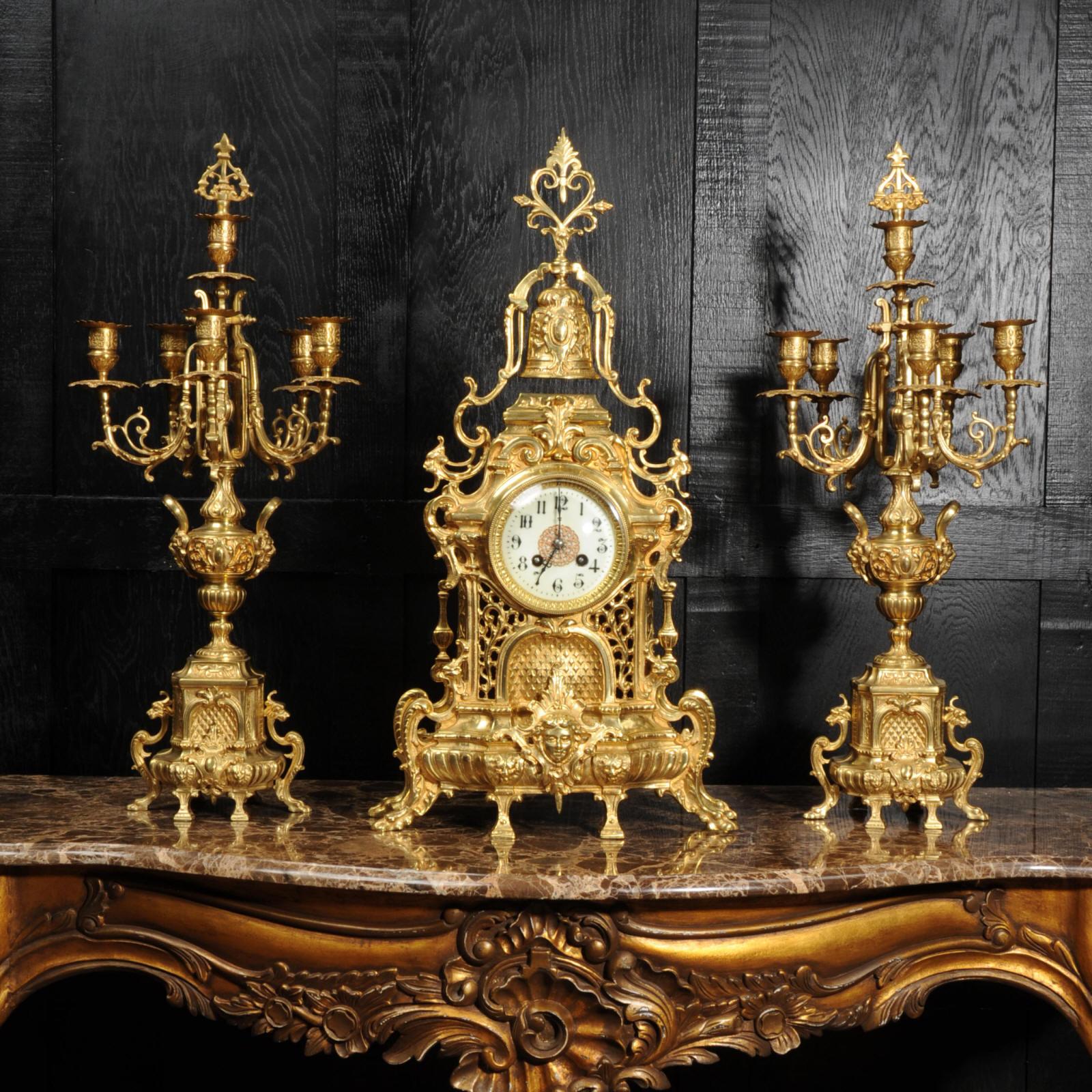 A large and impressive original antique French Baroque clock set, beautifully made in gilt bronze. It is heavily and crisply modelled with lions masks, hairy paw feet, flowing foliage and surmounted by a bell. The front of the clock is modelled as a