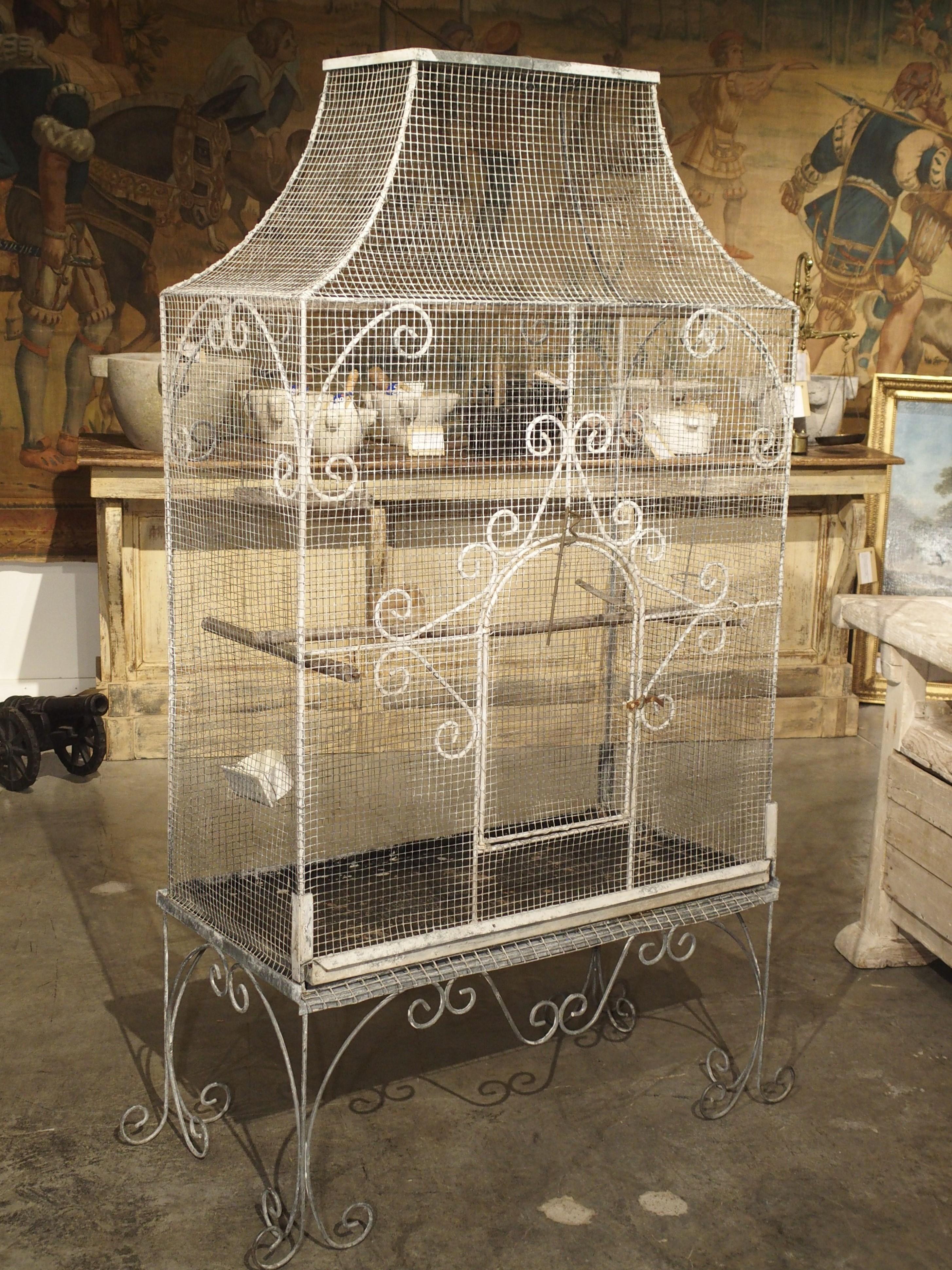 This large French birdcage is from circa 1915. The wire cage is in good antique condition with a working front door toward the bottom. There are hand bent C-scroll metal decorations on the upper corners and around the top portion of the door.

The