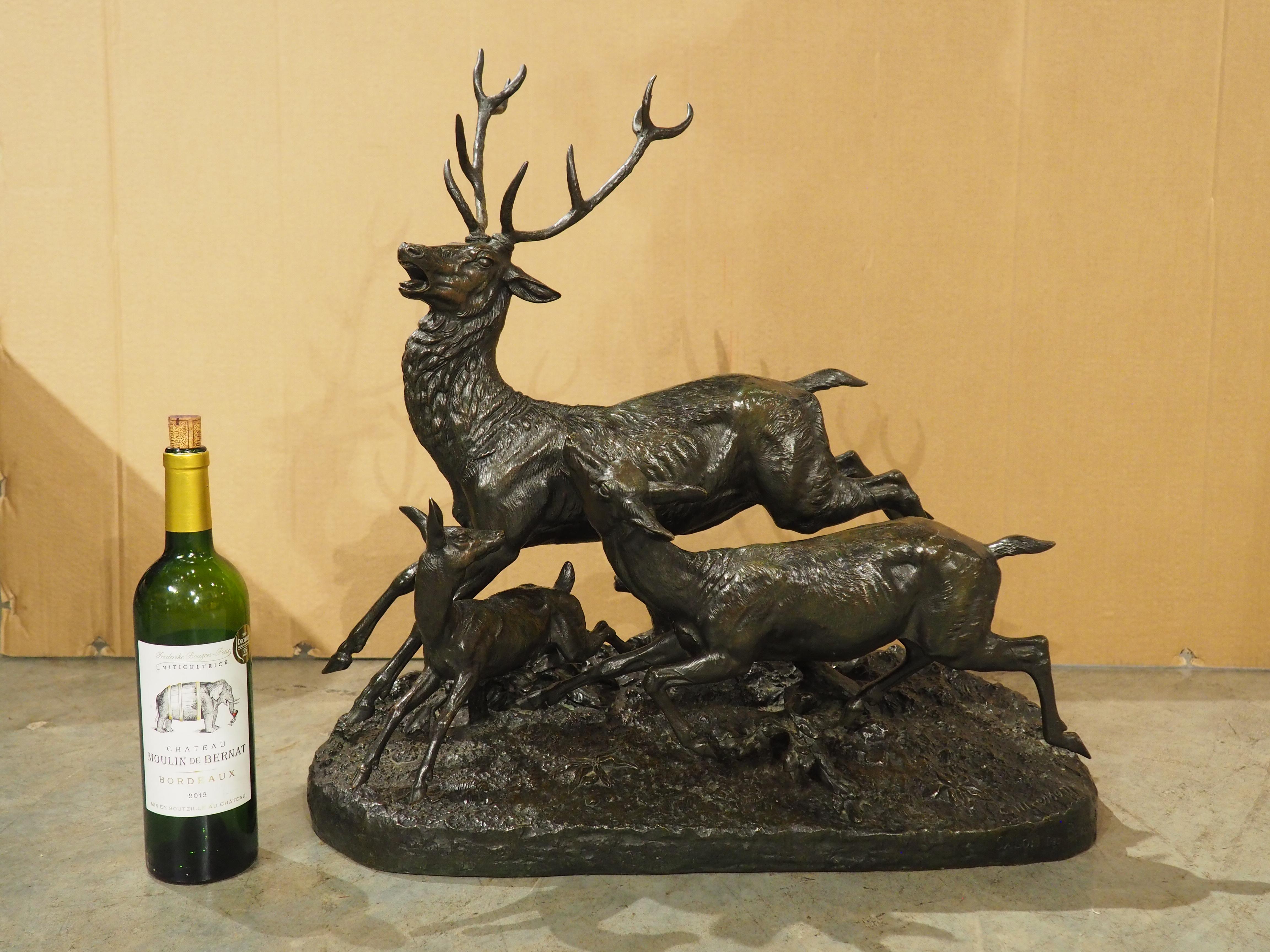 Cette grande sculpture française en bronze représente une famille de cerfs traversant un terrain rocheux parsemé de fleurs. Sculptée à la fin des années 1800 par Clovis-Edmond Masson, la sculpture présente un mouvement fantastique, les trois cerfs