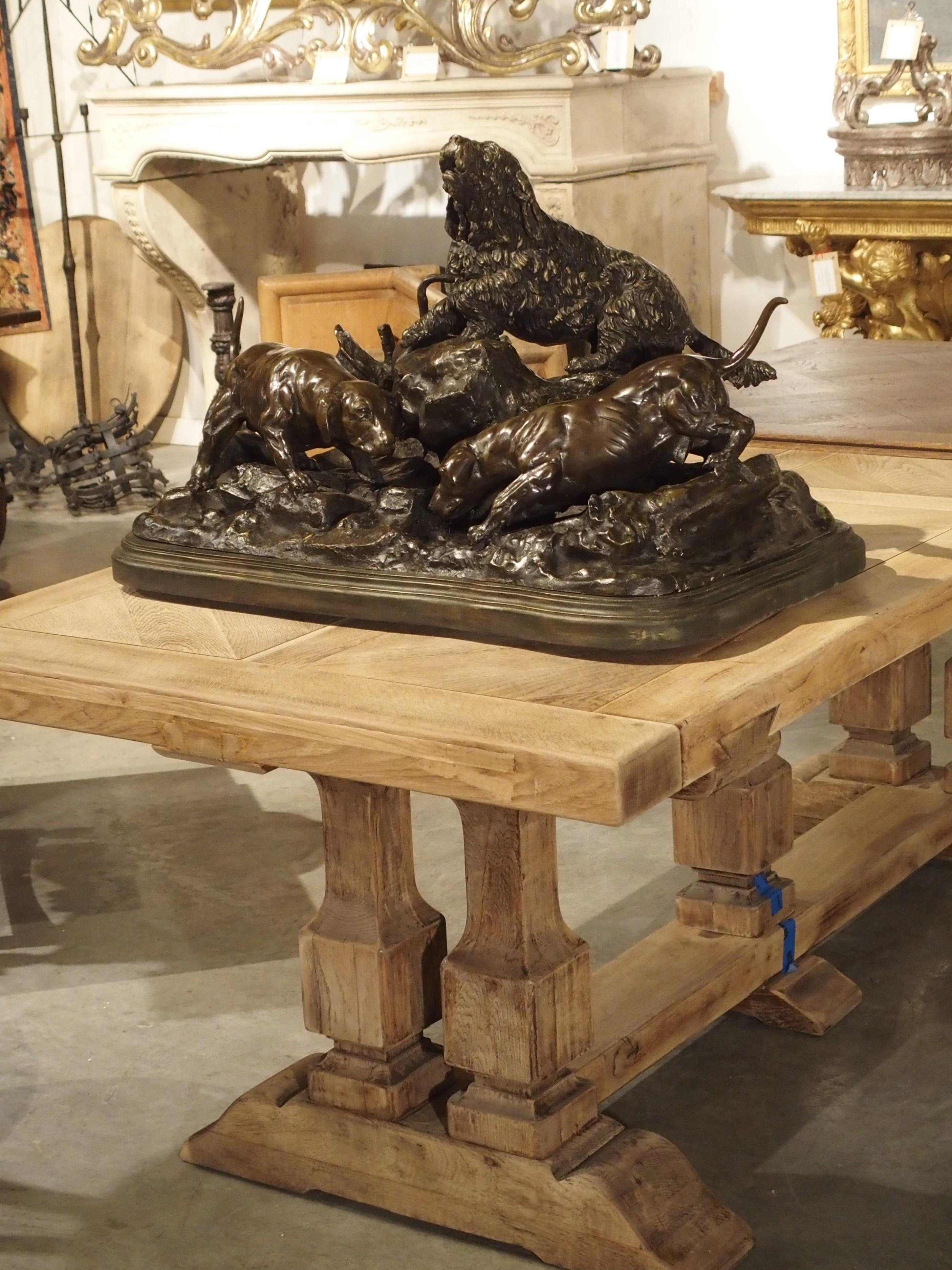 This large cast bronze sculpture of three hunting dogs sitting atop a plinth is signed Jules Moigniez, who was a prominent French animalier sculptor of the mid-late 1800s. The bronze group has a rich dark green/brown coloration, and has been mounted