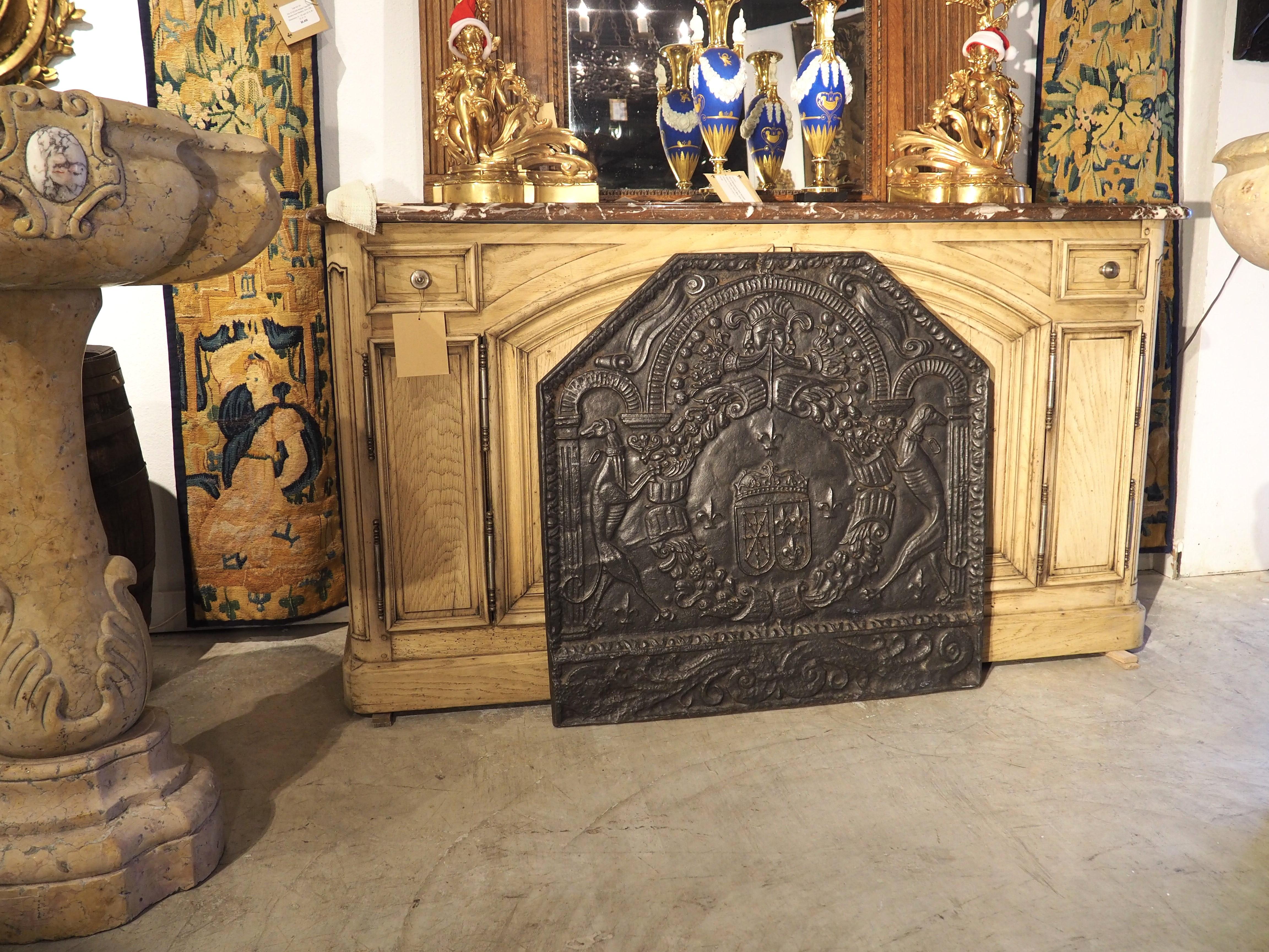 Crafted circa 1880, this cast iron fireback once graced the back of a fireplace in France. The rectangular fireback has an angular arched top with an egg and dart border along all edges. A central heraldic display depicts the arms of King Louis XIII