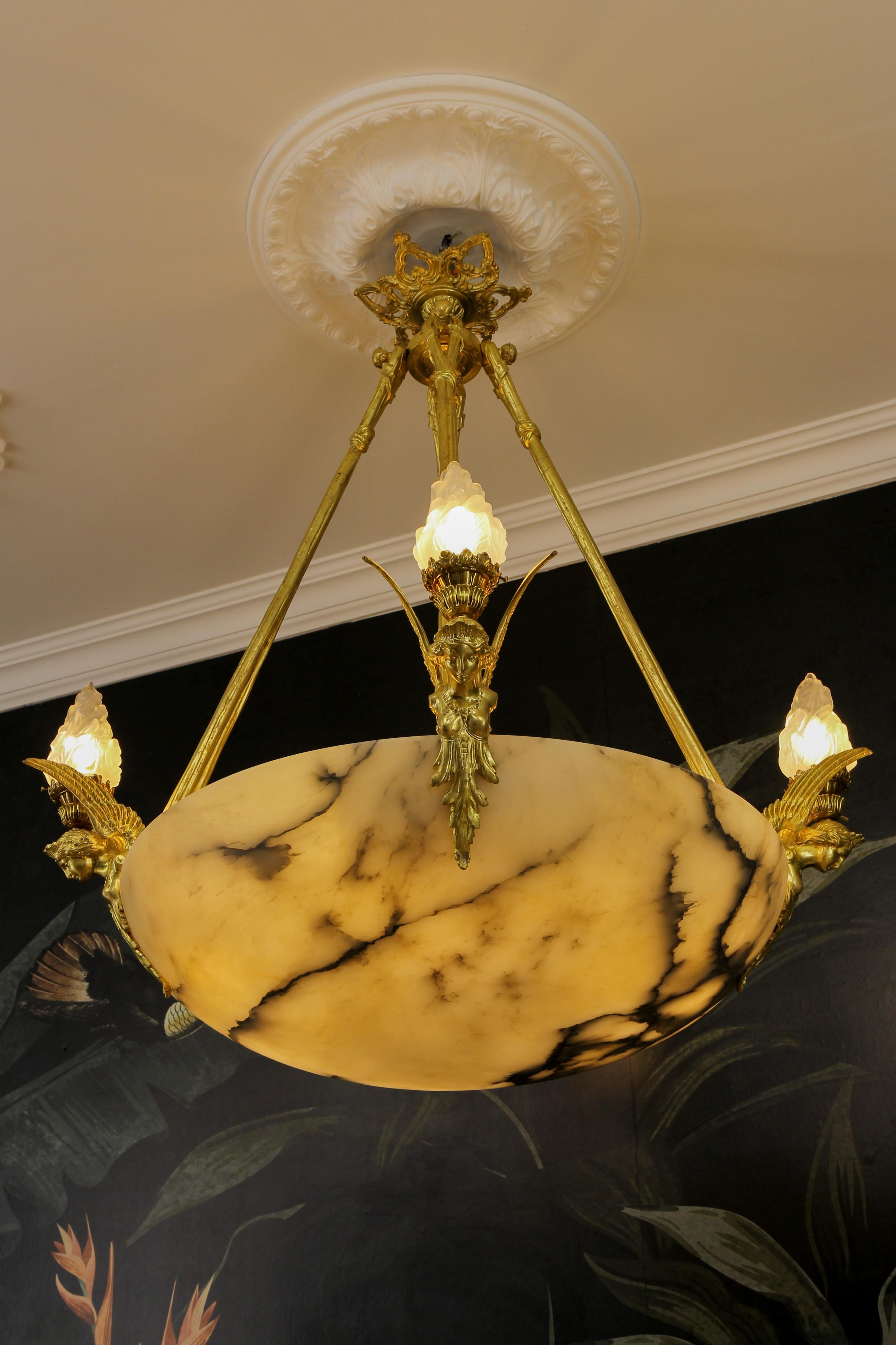 Large antique French Empire-style alabaster, frosted glass, and bronze pendant chandelier from circa 1890.
An impressive and large twelve-light alabaster pendant chandelier from the late 19th century. The beautifully veined large alabaster bowl with