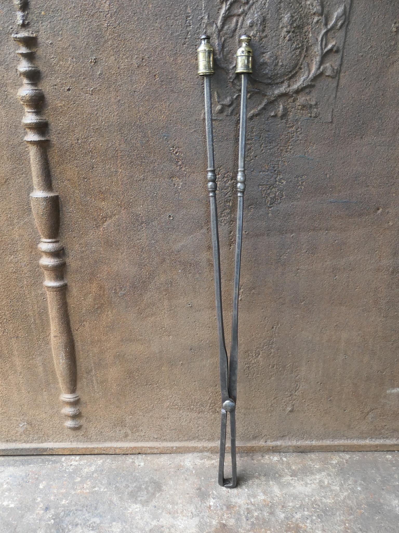 Large 19th century French Napoleon III fireplace tongs made of wrought iron. The handle is decorated with brass. The fire tongs are in a good condition and are fully functional.