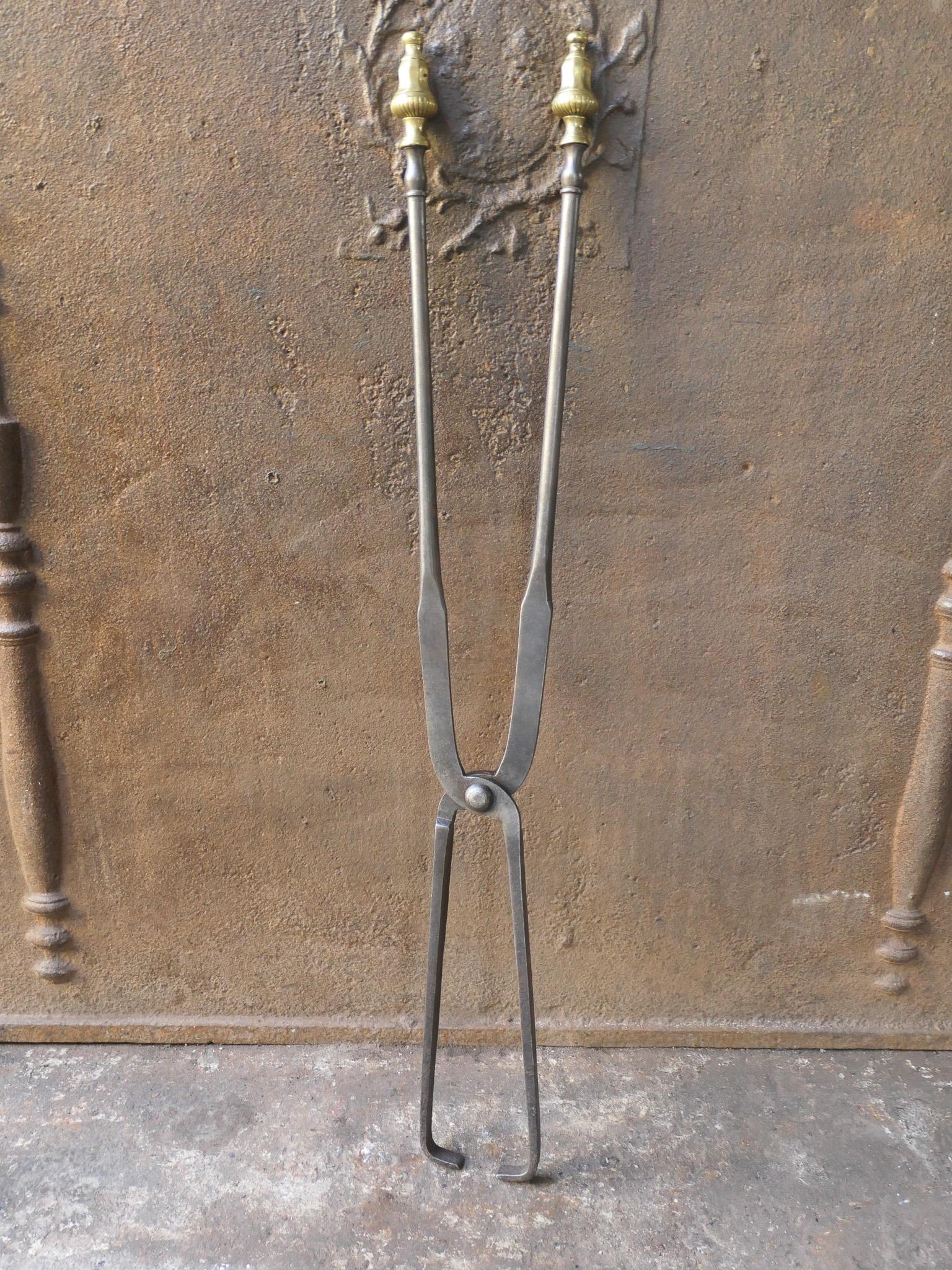 Large 19th century French Napoleon III fireplace tongs made of wrought iron. The handles are made of brass. The fire tongs are in a good condition and are fully functional.