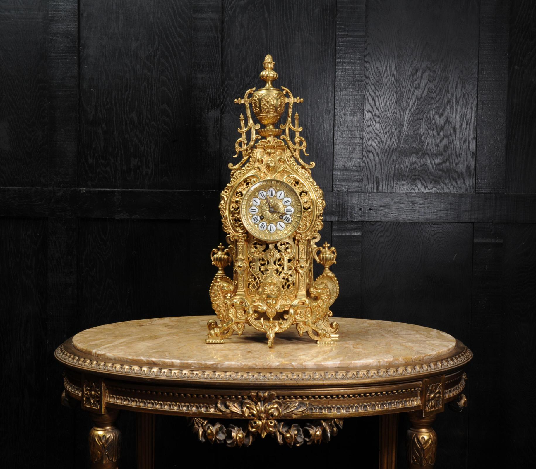 A large and impressive original antique French gilt bronze clock, circa 1880. It is Baroque in style, mythical creatures support the clock on a stylized sea of scrolls. Elaborate twirling foliage forms a fretted front to allow a glimpse of the