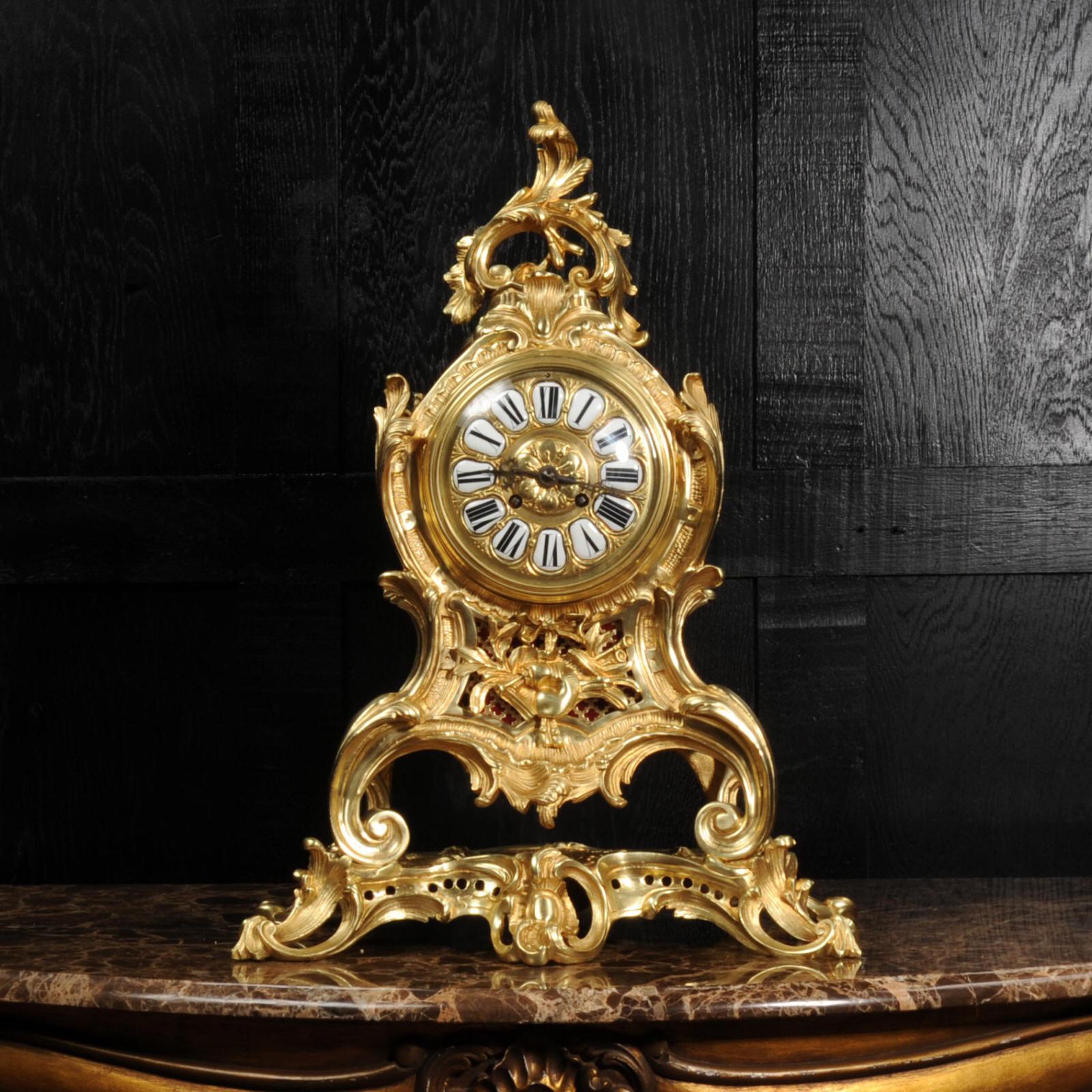 A Substantial and fine Rococo clock of gilded bronze, circa 1870. The case formed in the Louis XV style of bold scrolling acanthus standing upon a naturalistically modelled base. To the top, an arched Rococo flourish of scrolls and leaves. To the