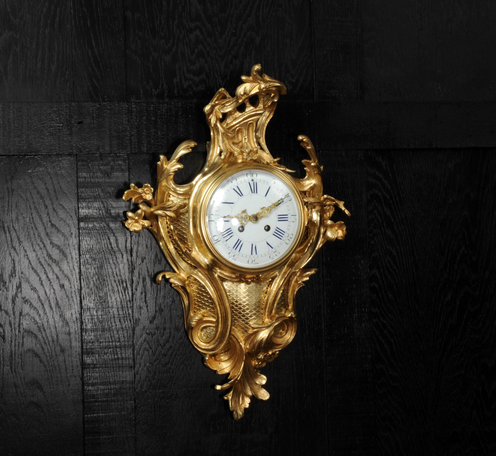 A large and stunning original antique French Cartel Wall clock in finely gilded bronze, dating from around 1880. Elegantly designed in the Rococo style of Louis XV, it is formed of bold, scrolling acanthus mounted with upward scrolling flowers.