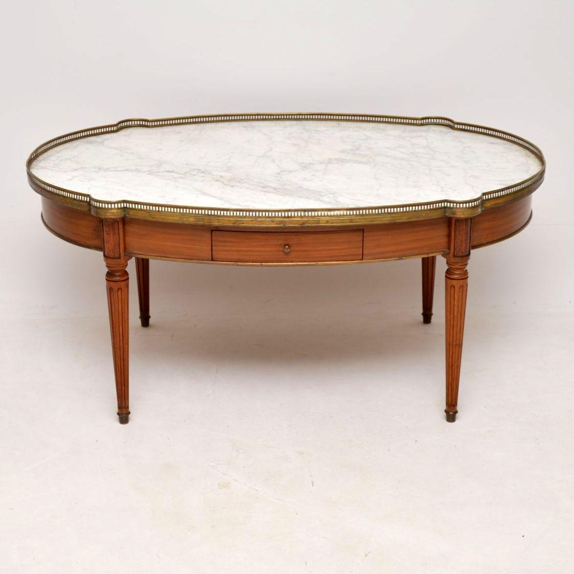 Large well shaped antique French walnut coffee table with a marble top surrounded by a pierced gilt bronze gallery. It’s in good original condition and I would date it to around the 1910s-1920s period. This table has some lovely features. There are