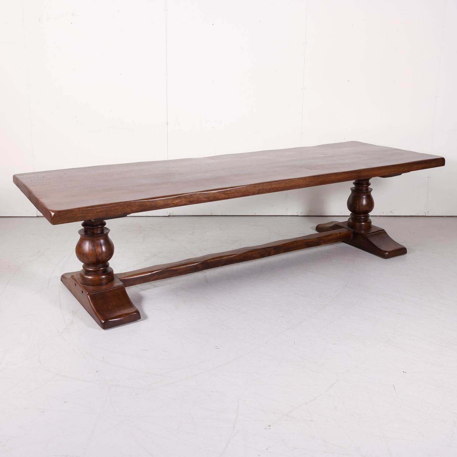 Large antique French monastery trestle table handcrafted of solid oak in Normandy, circa early 1900s, Supported on an oak base by a pair of hand carved baluster legs, each resting on a carved 