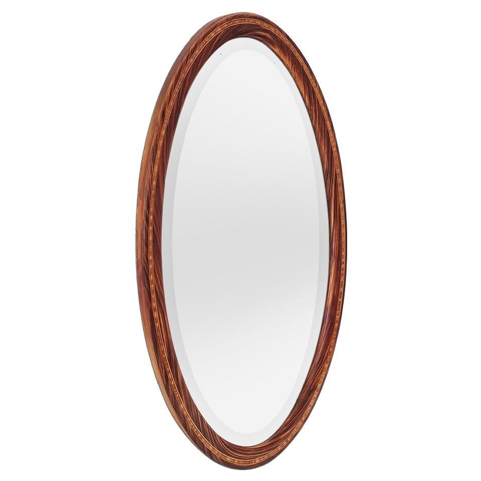 Large antique Art Deco oval mirror, circa 1926. The frame is decorated with painted imitation wood and painted marquetry (Faux bois). The antique glass mirror is beveled and bears the inscription “F 27.2.26” on the back. Frame width: 4.5 cm / 1.77