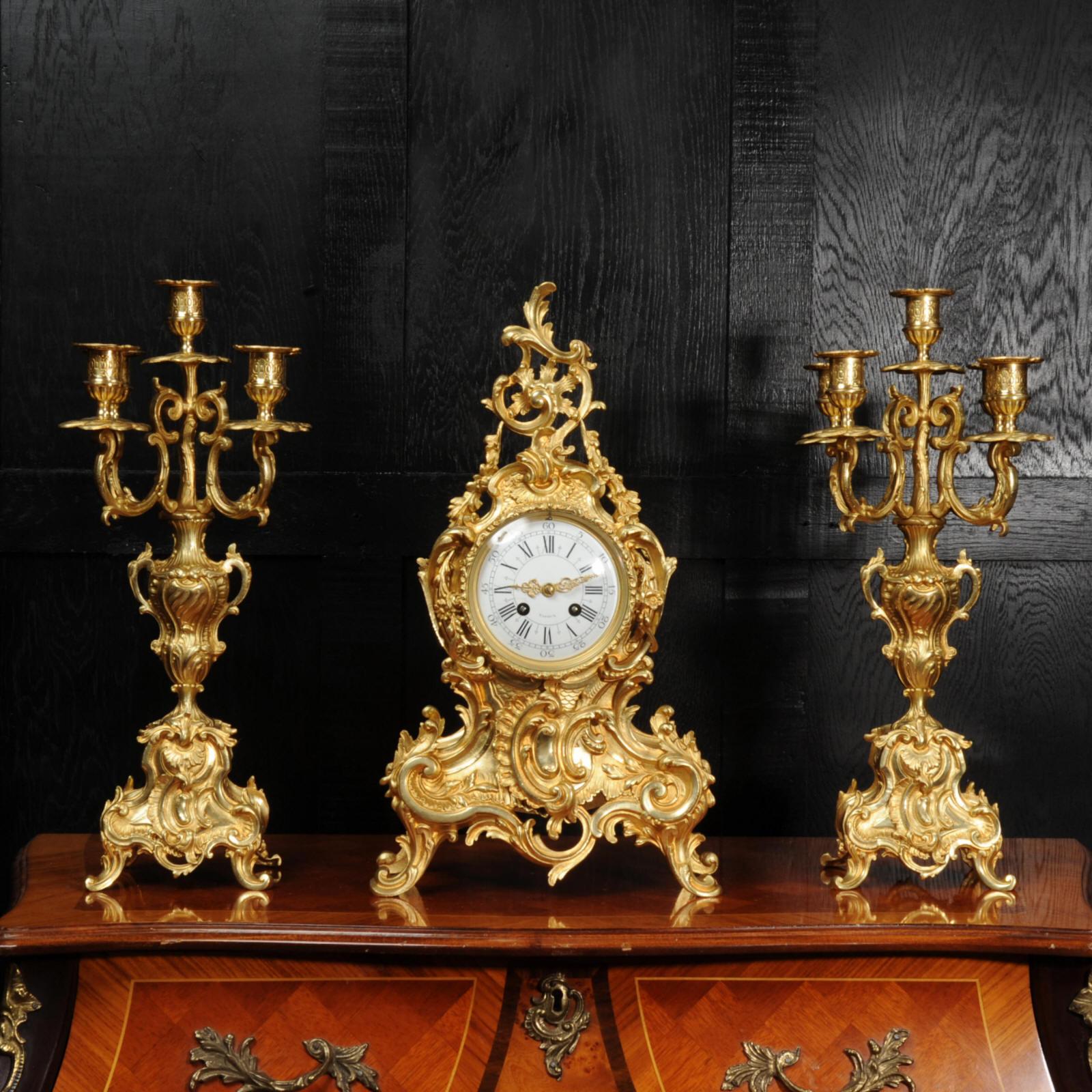 A stunning and large original antique French gilded bronze clock set, circa 1880. It is of the most beautiful Rococo style, waisted case decorated with 'C' scrolls, acanthus leaves and floral swags. Candelabra have 4 elaborate acanthus arms held