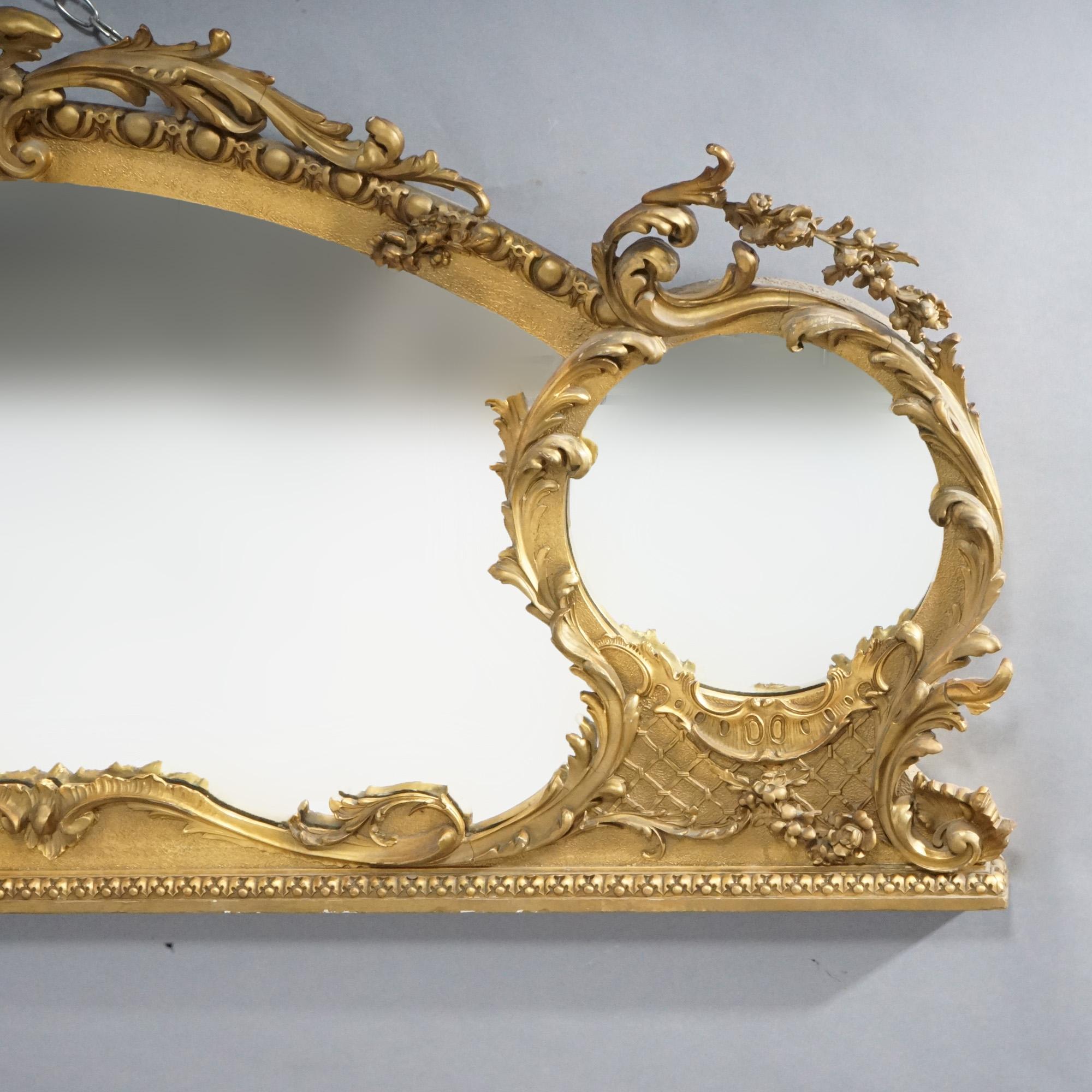 An oversized French Rococo over mantel mirror offers giltwood frame in scroll, foliate and lattice form and having large primary mirror flanked by two smaller, 19th century

Measures- 31.5'' H x 59.25'' W x 7'' D.