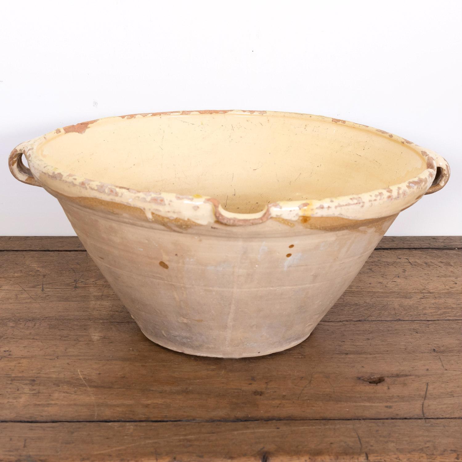 A large 19th century French terracotta tian bowl complete with both handles and pouring spout having an unglazed exterior and a beautiful pale yellow glaze to the interior and lip, circa 1880s. Earthernware tian bowls like this are considered