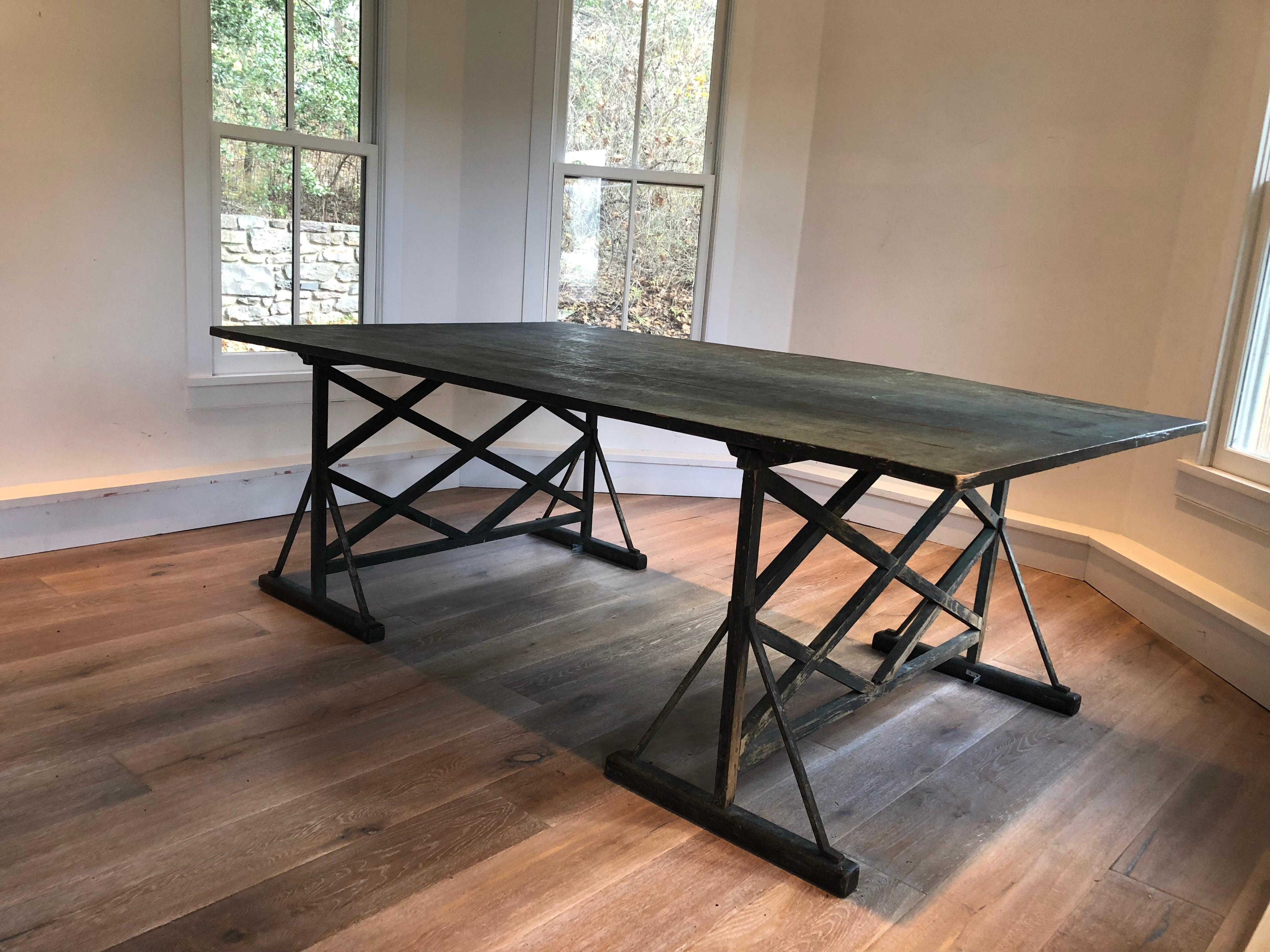 A large green painted antique French trestle table. Wide plank top with lattice legs.
