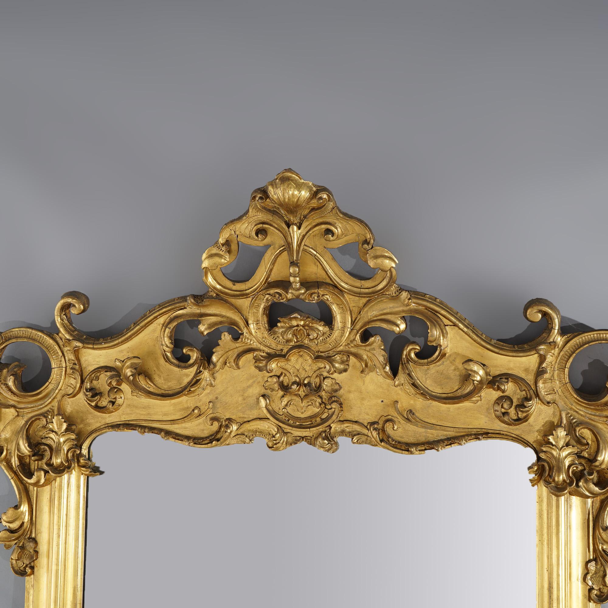 An oversized antique French Victorian over mantle mirror offers carved giltwood frame with exaggerated scroll and foliate crest having central cartouche, c1880

Measures- 71''H x 54''W x 12''D; 50'' x 36.5'' sight

Catalogue Note: Ask about