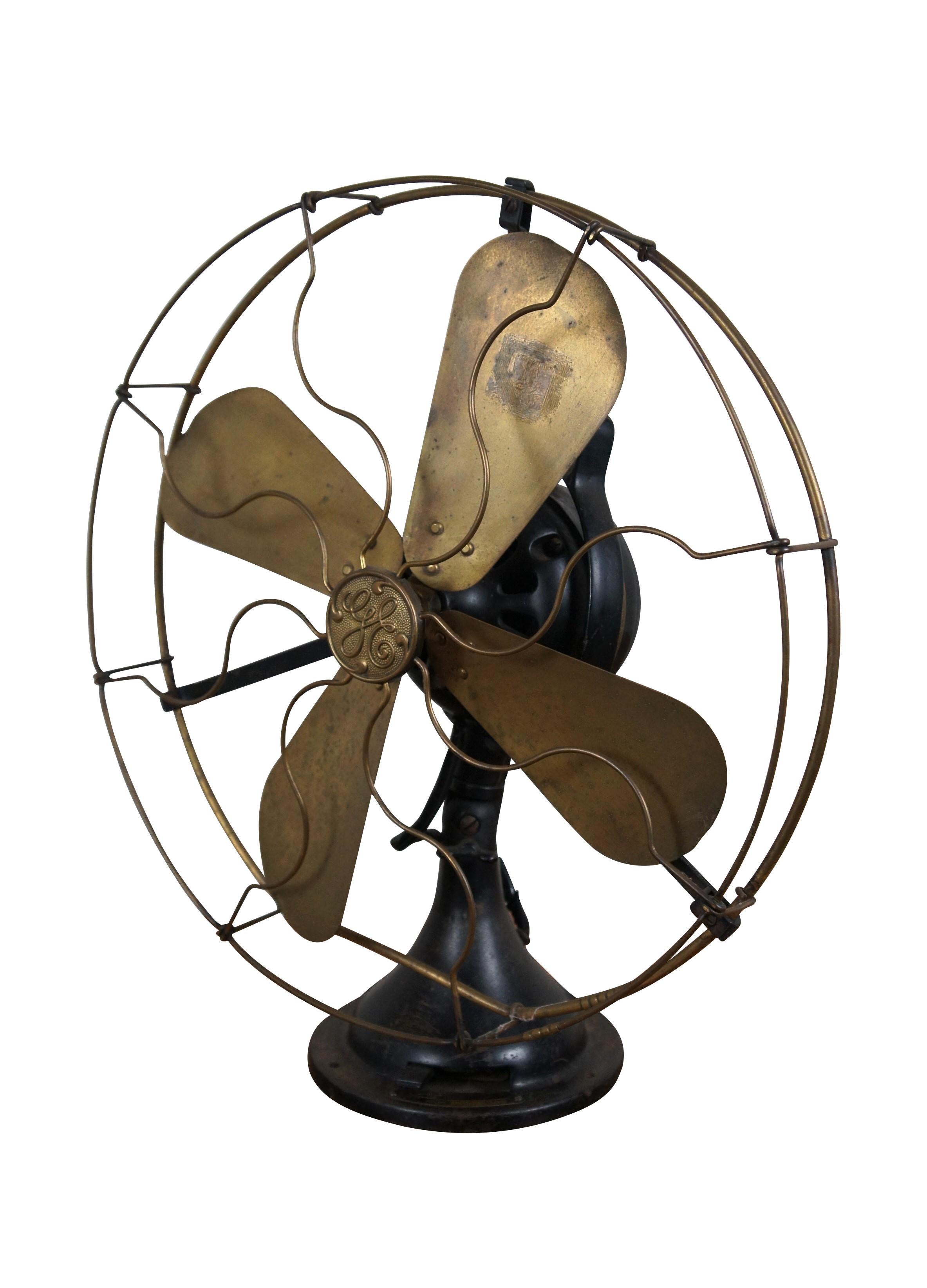 Ventilador de sobremesa grande antiguo de 1915 con mango de 2 estrellas / bucle, de General Electric. Carcasa de acero pintado de negro con cuatro palas / alas de latón y jaula con barras serpentinas. Tres velocidades; oscilante; interruptor