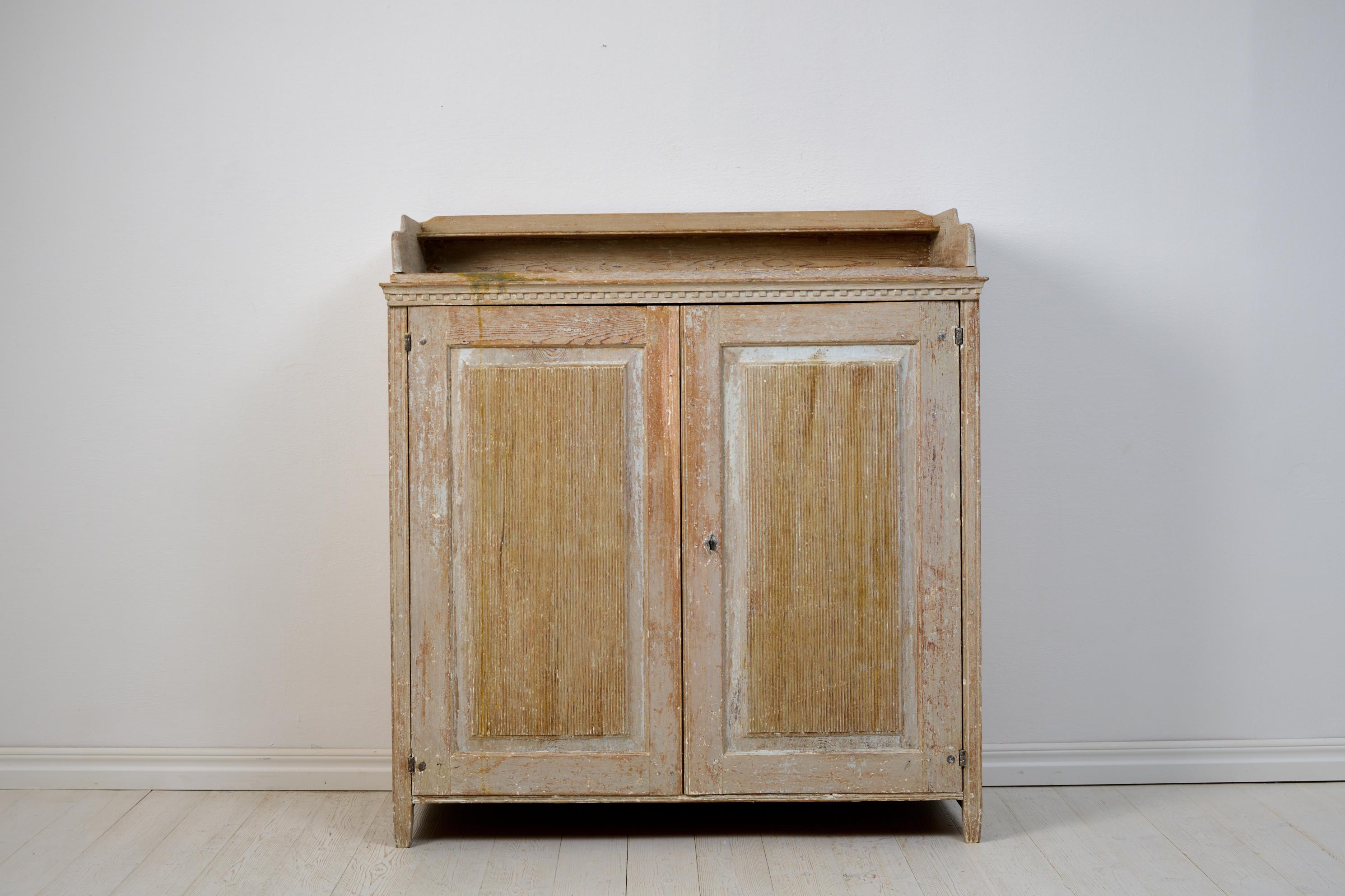 Large genuine Gustavian sideboard from Northern Sweden, made around 1810. The sideboard is crafted from solid pine and scraped by hand down to the original paint. It is adorned with carved wooden decor, and an unusual detail is that the short ends