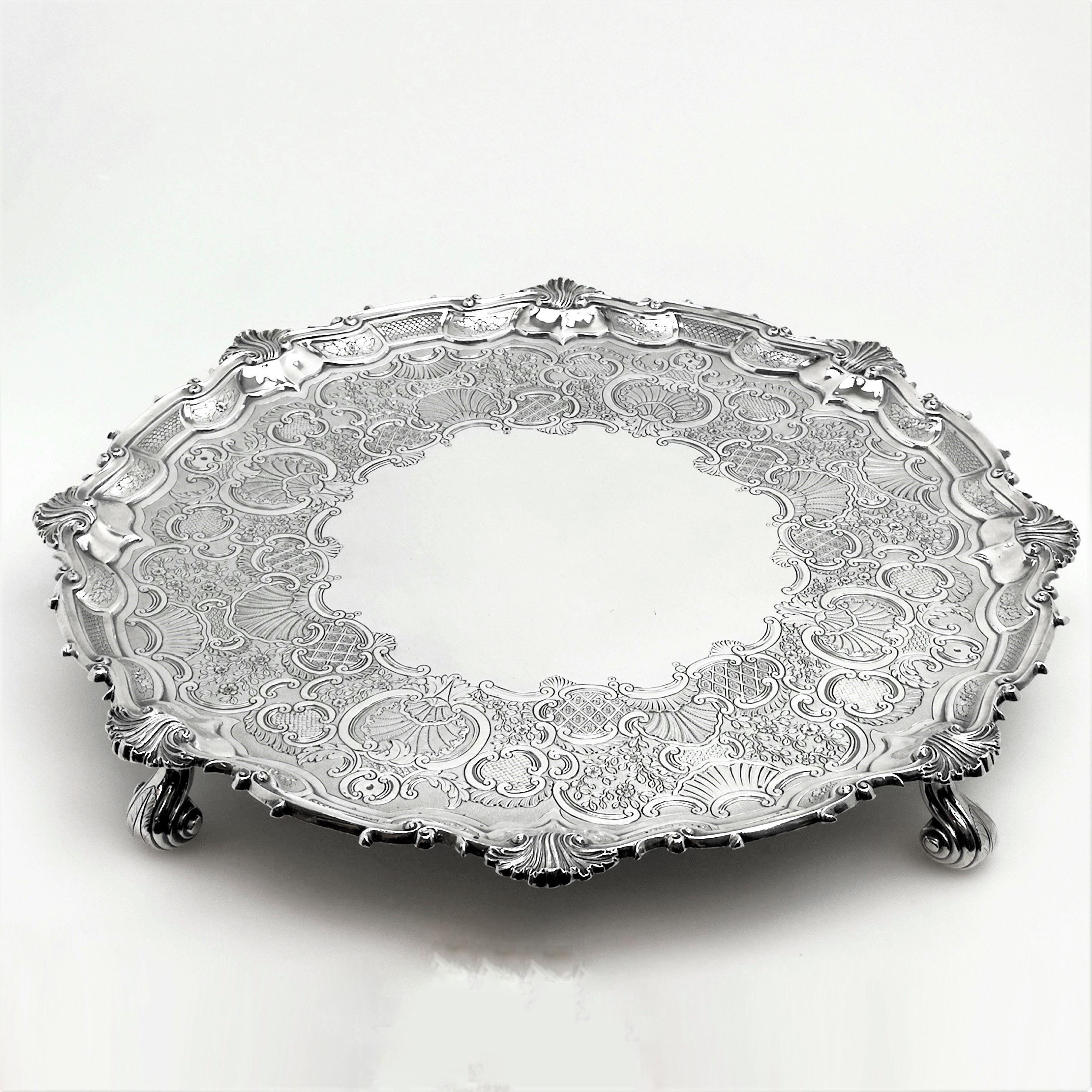 An enormous antique Georgian solid Silver Salver standing on four impressive scroll feet. The Salver has a shaped border and the Salver is embellished with an ornate shallow chased and engraved design around a central cartouche. 
 
 Made in London