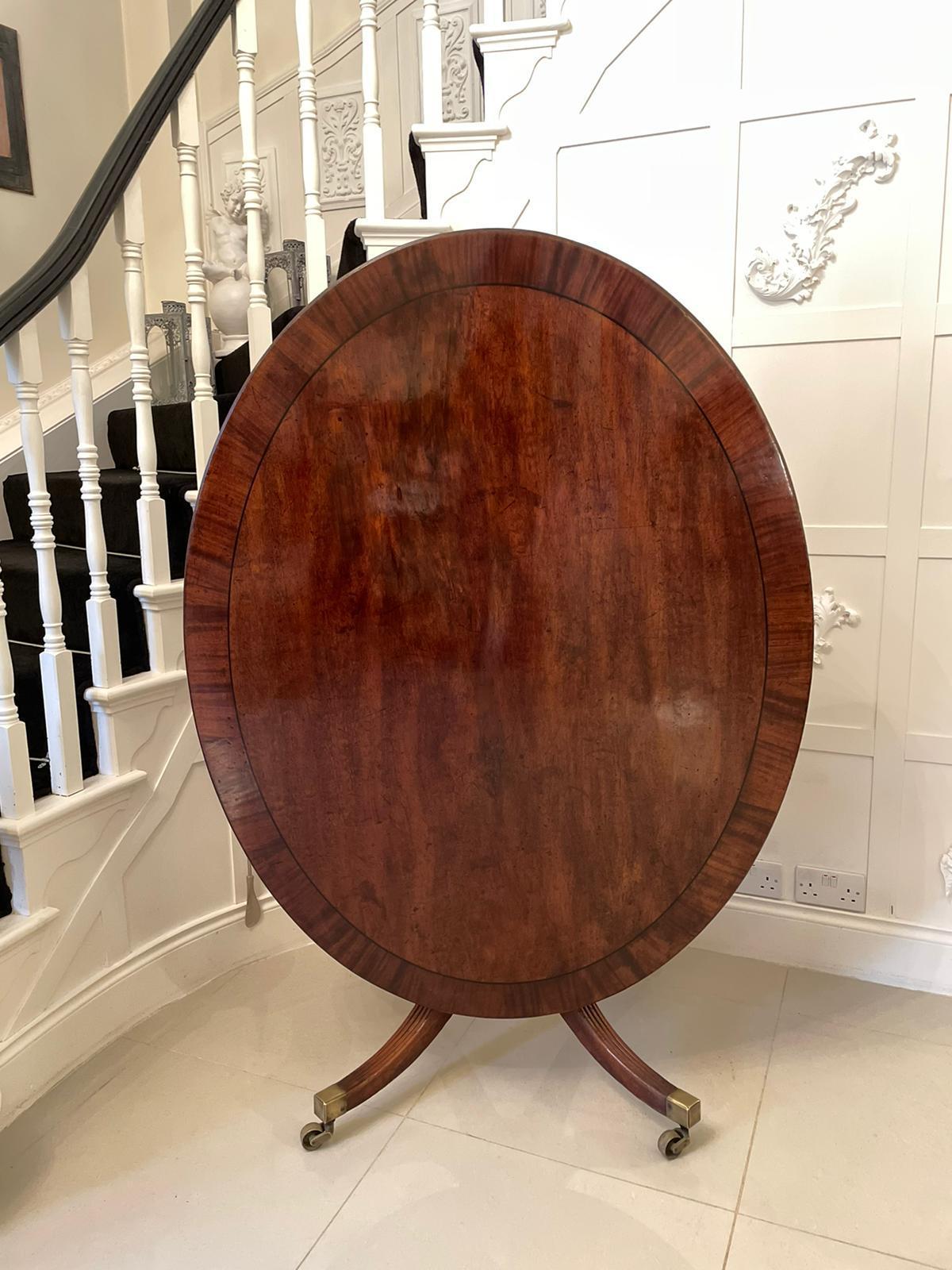 Large antique George III oval mahogany breakfast table having an outstanding oval mahogany crossbanded top with reeded edge. This wonderful example is supported by a beautifully turned column and raised on four reeded sabre legs, terminating in the