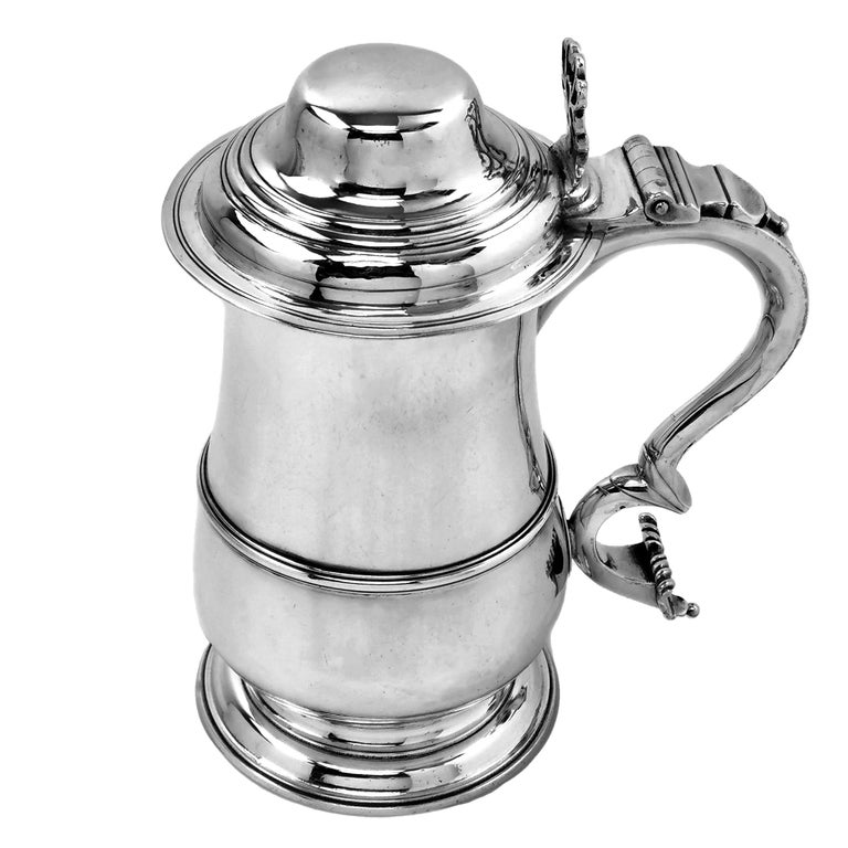 A classic Antique George III silver quart Tankard with a traditional baluster shaped body. The Tankard has an domed lid with an ornate thumb piece above an impressive scroll handle. The handle has the initials W N M engraved. 

Made in London,