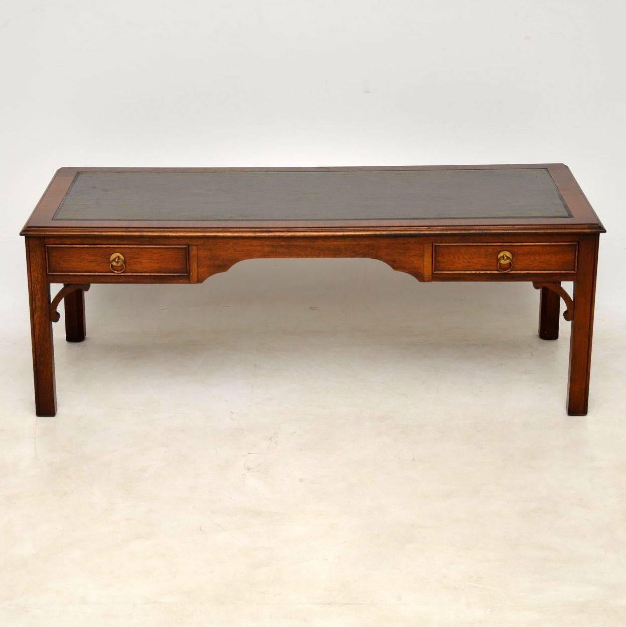 Large antique Georgian style leather top mahogany coffee table. It’s in good original condition and is about 50 years old. This coffee table has a tooled leather top, drawers on one side and dummy drawers on the other side. The legs are chamfered &