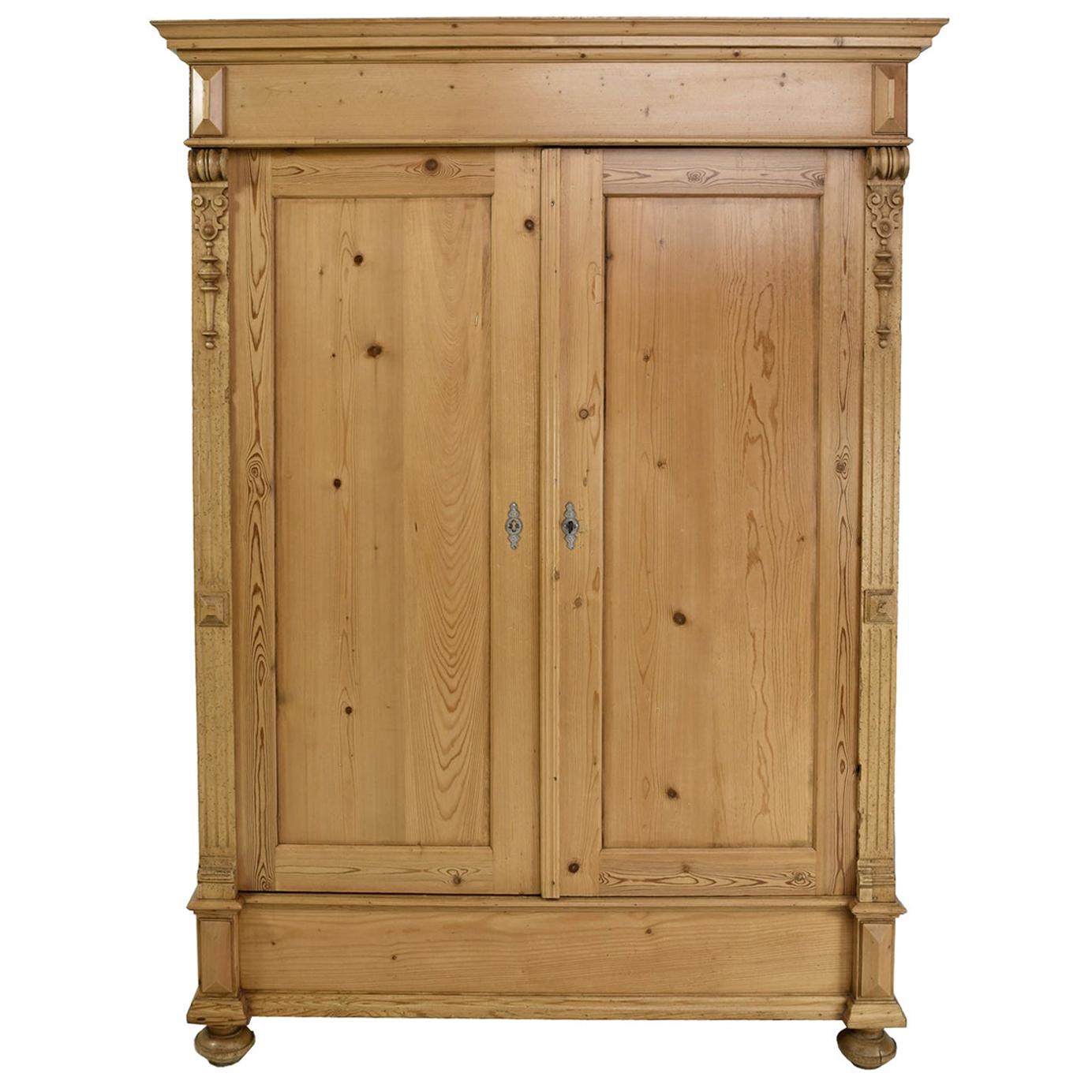 This German Grunderzeit pine armoire has all of it original appliques, turned bun feet. Nickel-plated key plates and working lock with key. The inside comes with a hanging bar and 3 adjustable shelves. It is the perfect depth for hanging cloths or