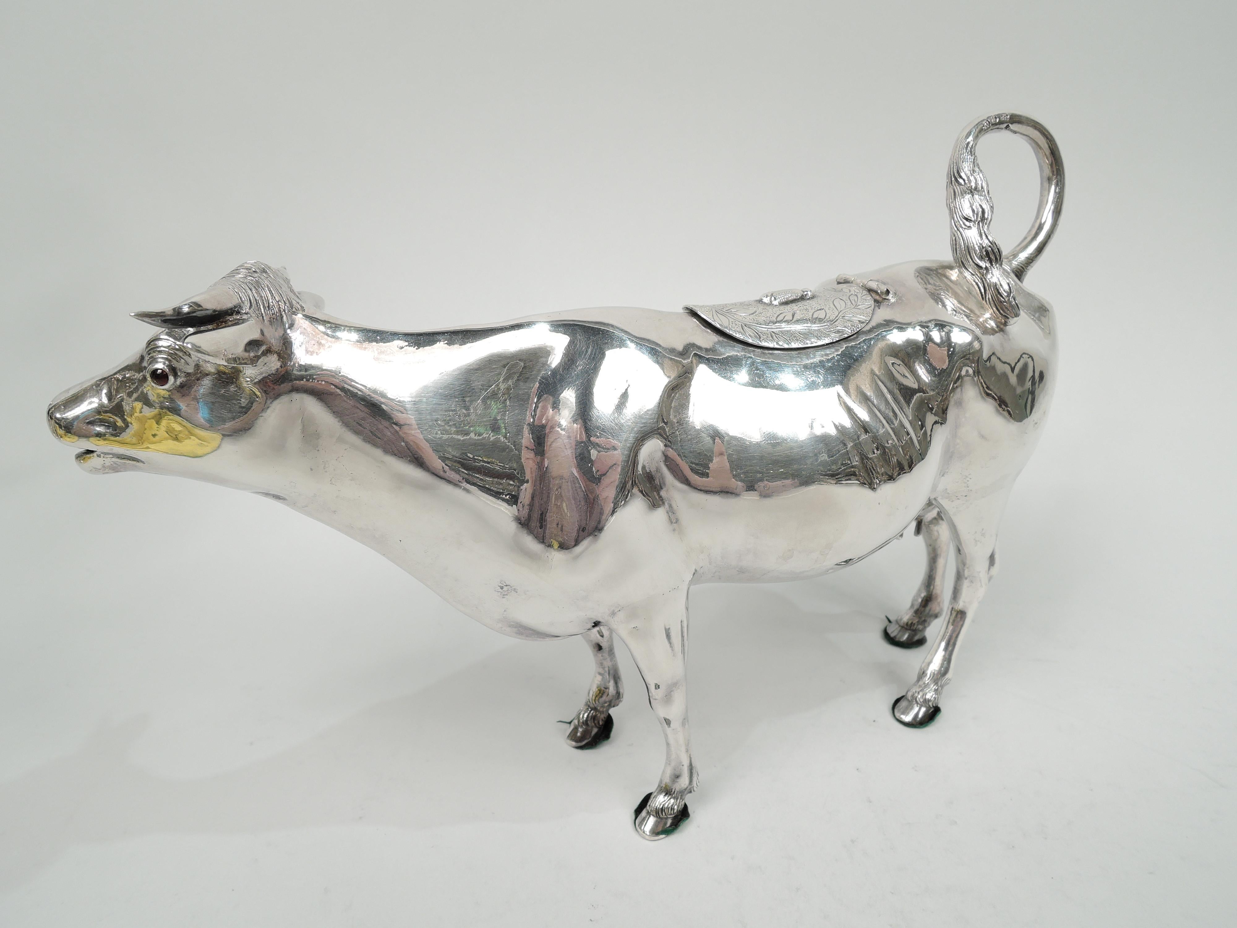 German 800 silver cow creamer, ca 1910. Stocky body with flexed ears, flicked-back tail handle, and hinged and stippled back flap with engraved wreath and applied fly finial. A gentle face with red-glass eyes and gaping-mouth spout. A capacious