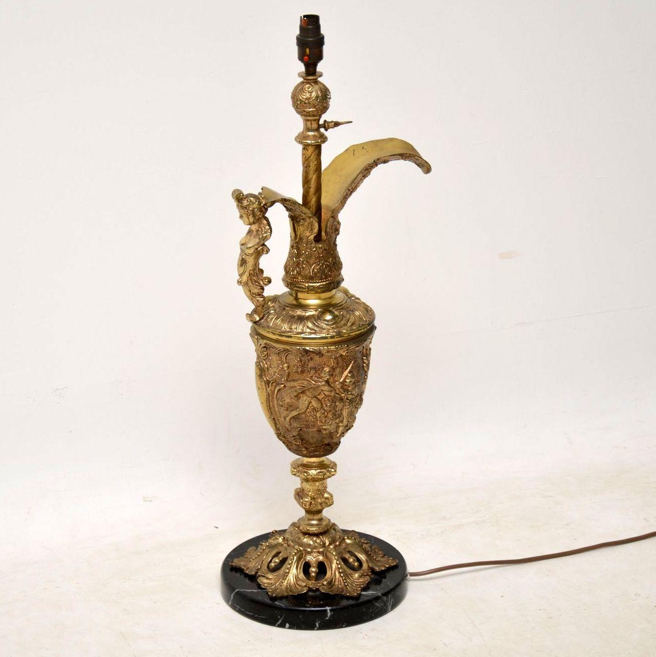 Large antique gilt metal lamp sitting on a marble base. It’s in excellent condition and has just been re-wired. This lamp is in the shape of a flagon with beautiful relief decoration all over. I would say it dates to circa 1950s period.

Measures: