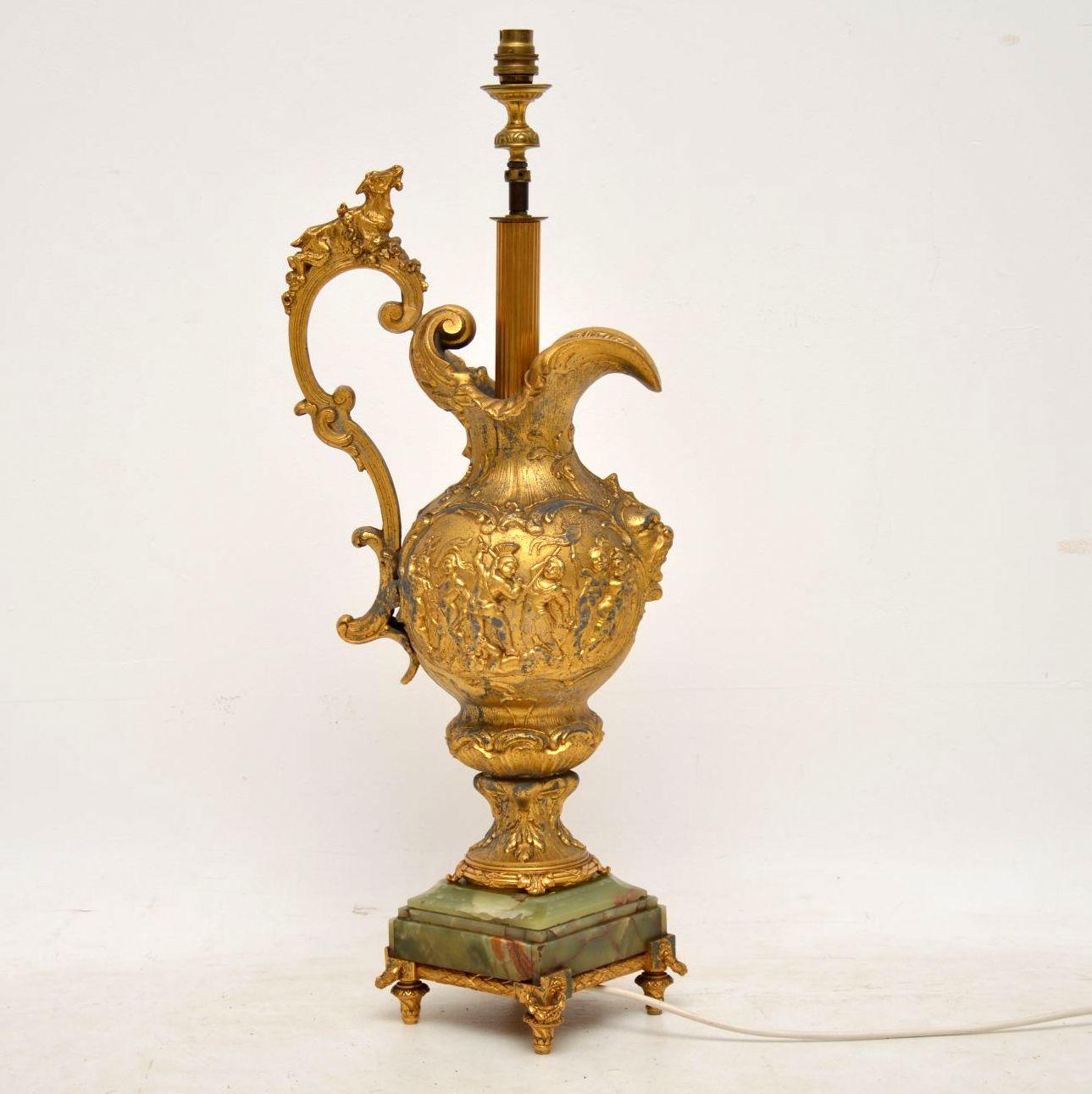 Large antique gilt metal lamp in the form of an embossed flagon with many fine details & sitting on an onyx base with gilt feet.

The gilding has a soft gold color & has been cleaned a bit but still could be cleaned more, if wished. I like it as