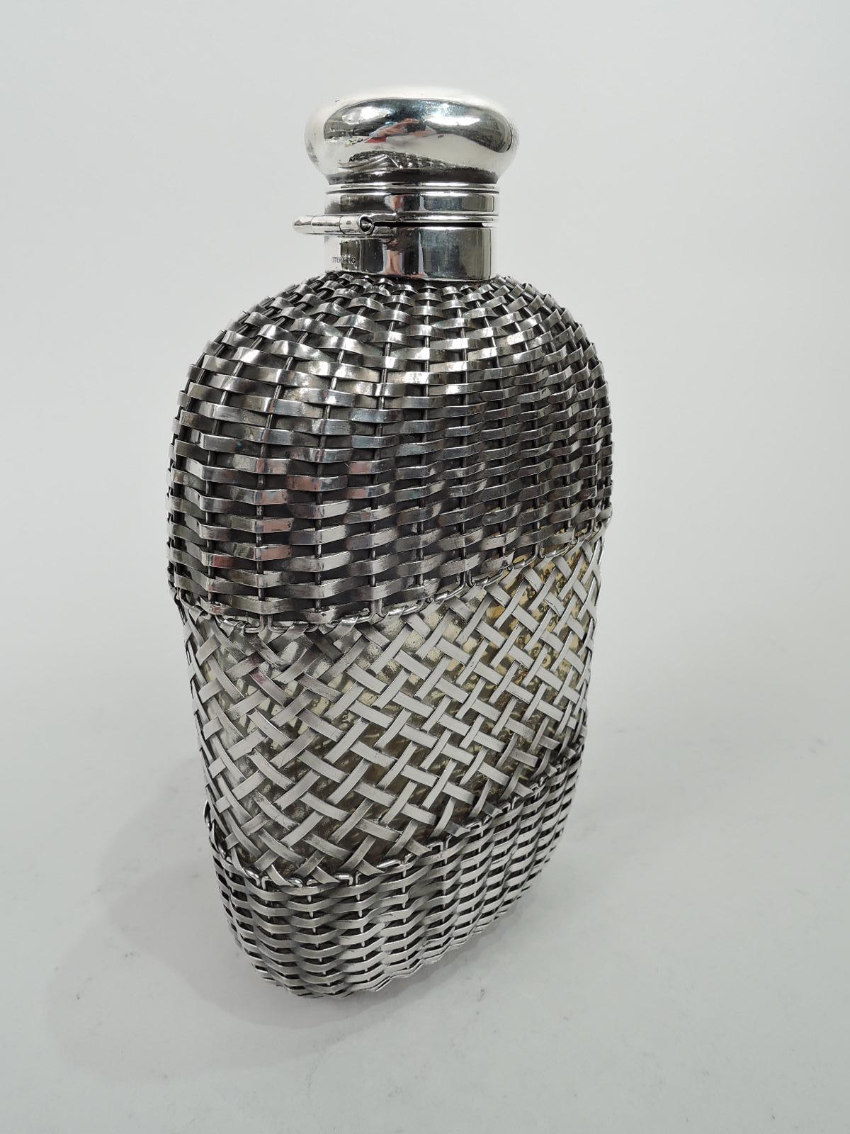 Large Edwardian flask. Made by Gorham in Providence in 1900. Rectilinear with flat front and back and curved sides in clear glass. Textural easy-grip sterling silver cage with dense weave at top and bottom and open lattice in center. Collar sterling