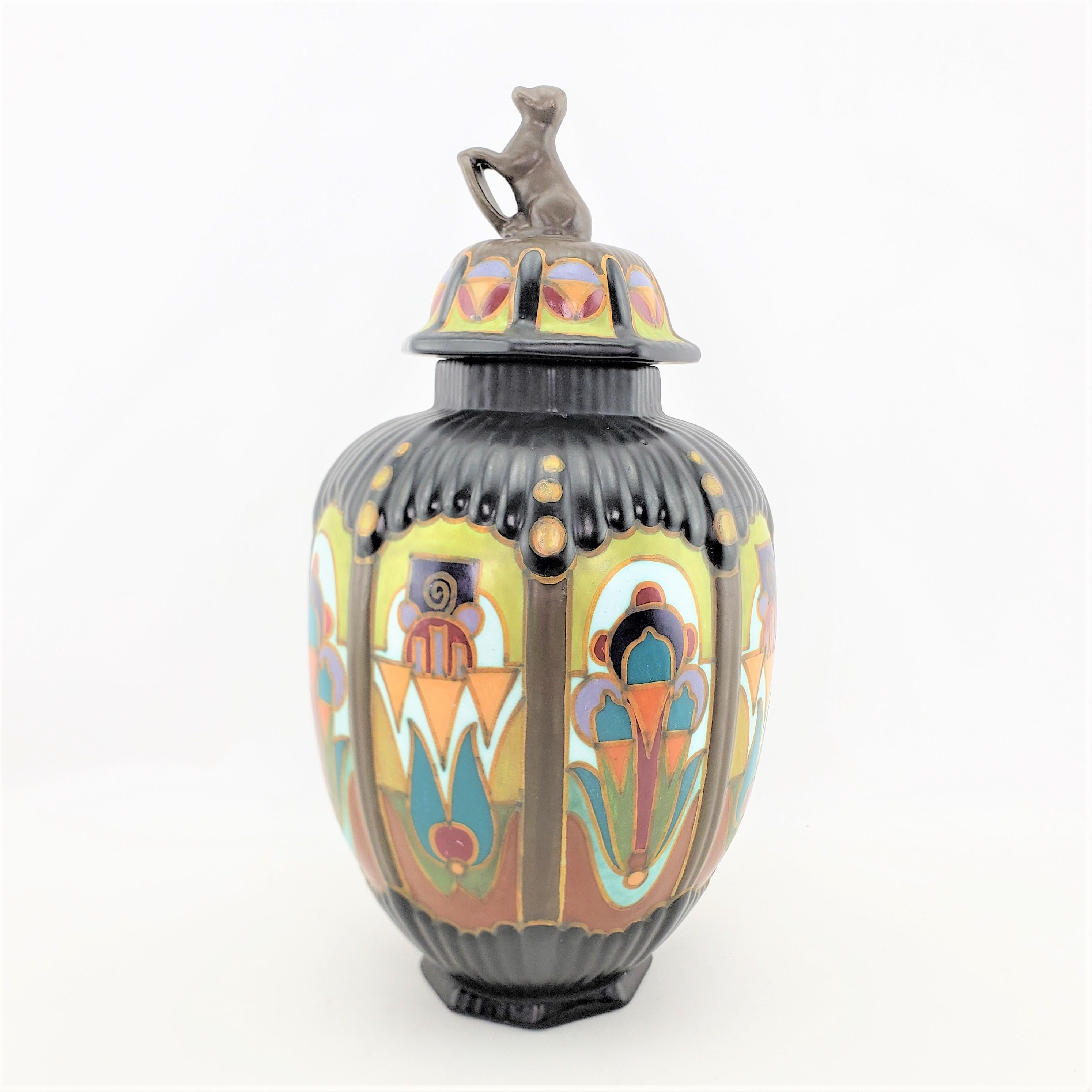 This large art pottery lidded vase or urn was made by Gouda of Holland in approximately 1920 in a period Art Deco style. The lidded vase is done with an octagonal rim and base with ribbed sides. The body of the vase is done with a black matte glaze