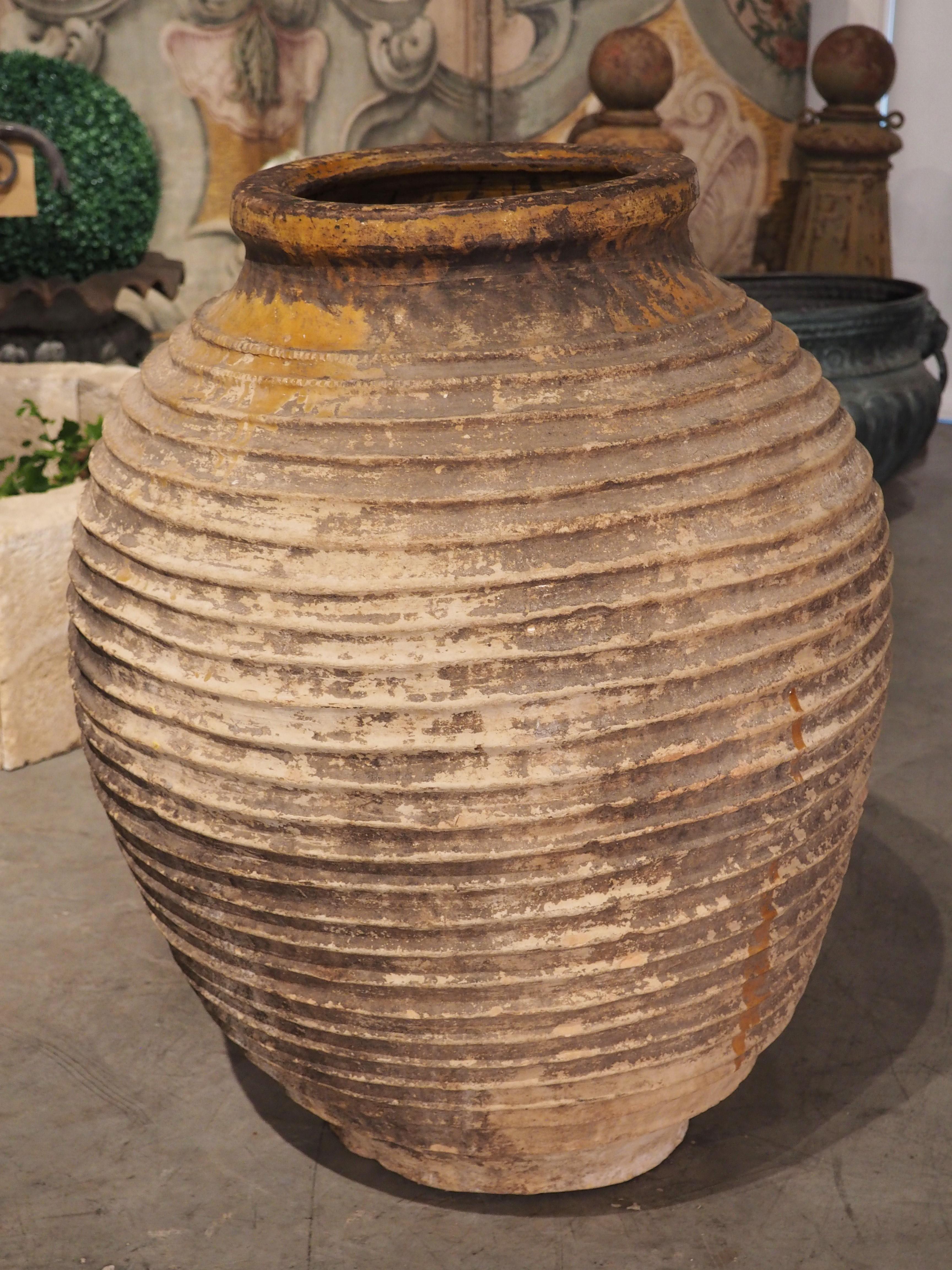 This ribbed terra cotta oil pot with partial ochre glaze was hand thrown circa 1850. The form is known as a koroniotiko, which comes from the town of Koroni (sometimes known as Corone), in the Peloponnese region of southern Greece. Koroniotiko have